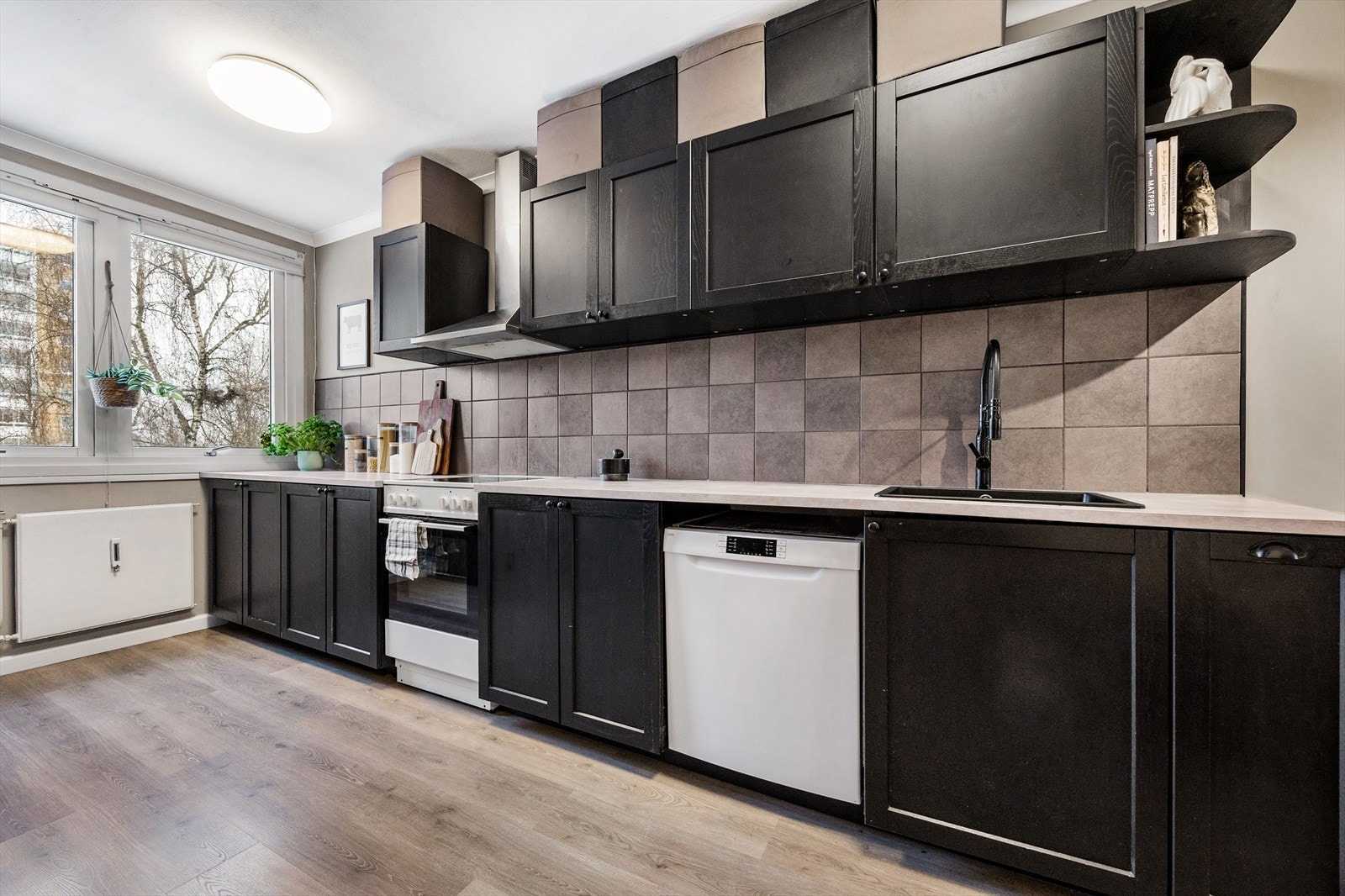 Kjøkkeninnredning med mørke fronter og rikelig med skap- og benkeplass. Galleribilde