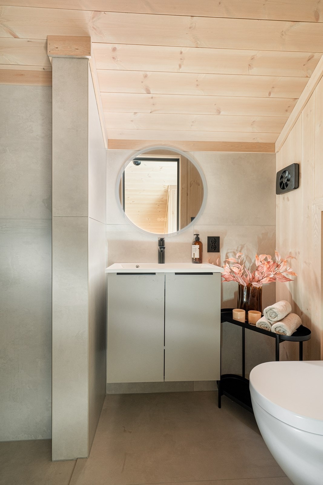 Lyst og pent bad med fliser på gulv og flis/ panel på vegger. Her er det dusjsone, vegghengt toalett, innredning med heldekkende hvit vask, underskap med slett front og rundt speil.
Det er varmekabler i gulv og ventilasjon via elektrisk styrt vifte. Galleribilde