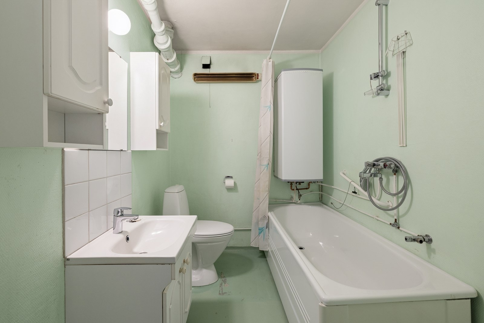 Bad/vaskerom innredet med servant nedfelt i baderomsinnredning, gulvmontert toalett og badekar. I tillegg til at det er opplegg for vaskemaskin. Galleribilde