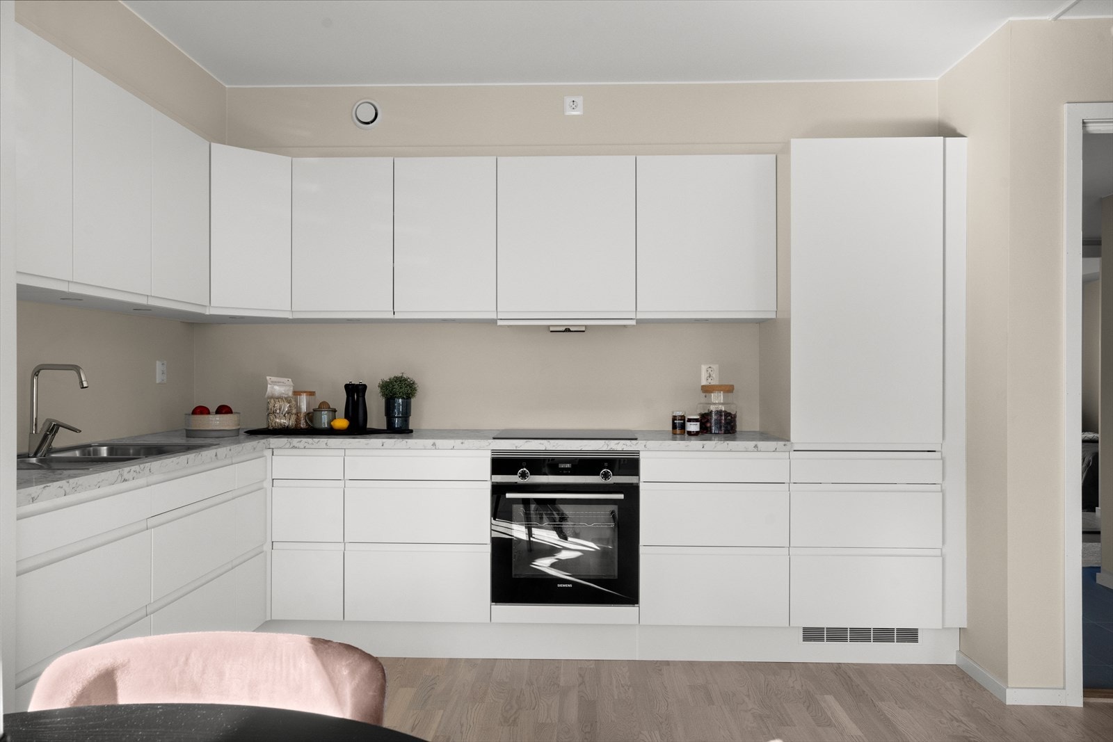 Stilrent kjøkken fra HTH med hvite slette håndtaksfrie fronter og laminert benkeplate i marmor utførelse. Galleribilde