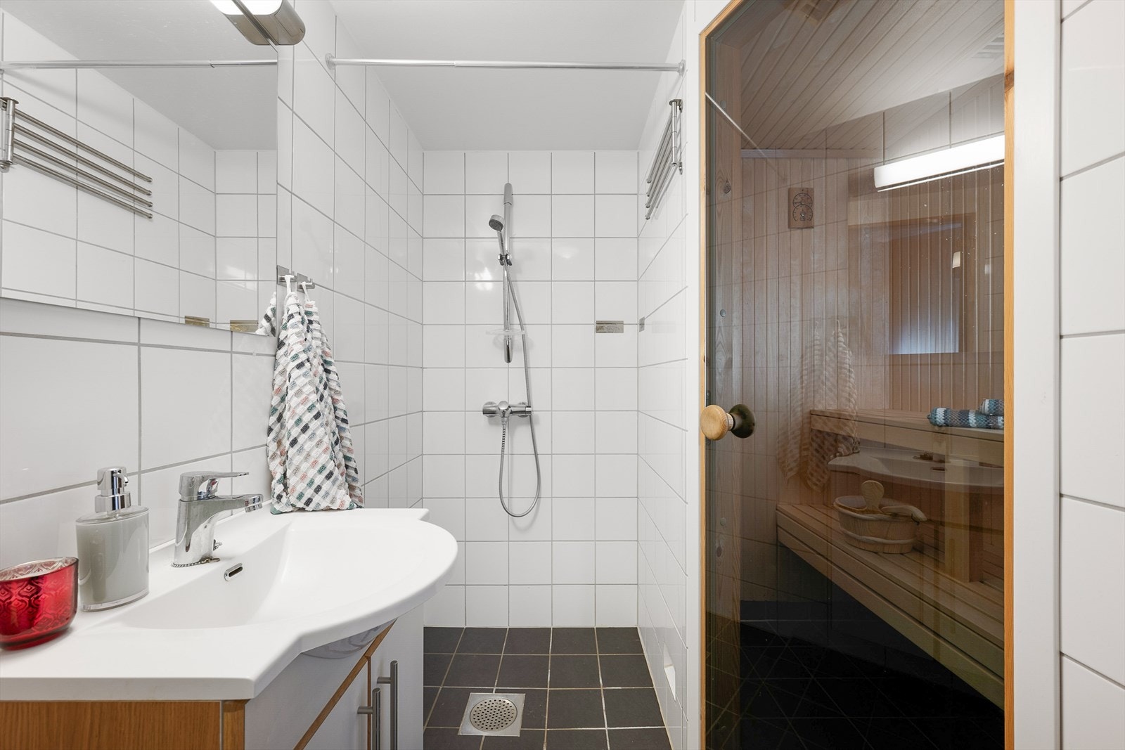 Lyst bad med dusjhjørne, servantinnredning og direkte tilgang til badstue. Galleribilde