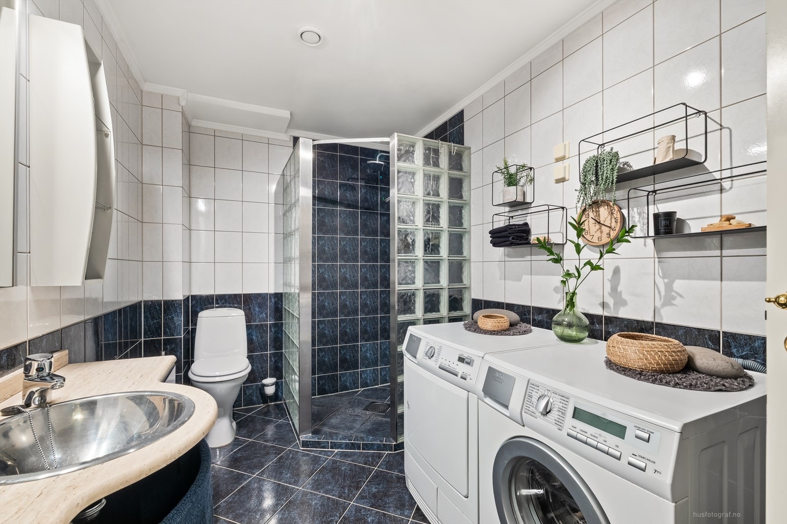 Badet har innredning med nedfelt vaskeservant, skuffeinnredning med benkeplate av stein. Det er monter hyller og høyskap. Galleribilde