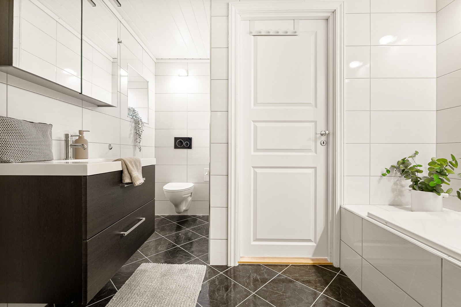 Flott helfliset bad innredet med vegghengt toalett, dusj, innfliset badekar, servant med møblement og speil med belysning. Vannbåren gulvvarme og elektrisk avtrekksventil. Galleribilde