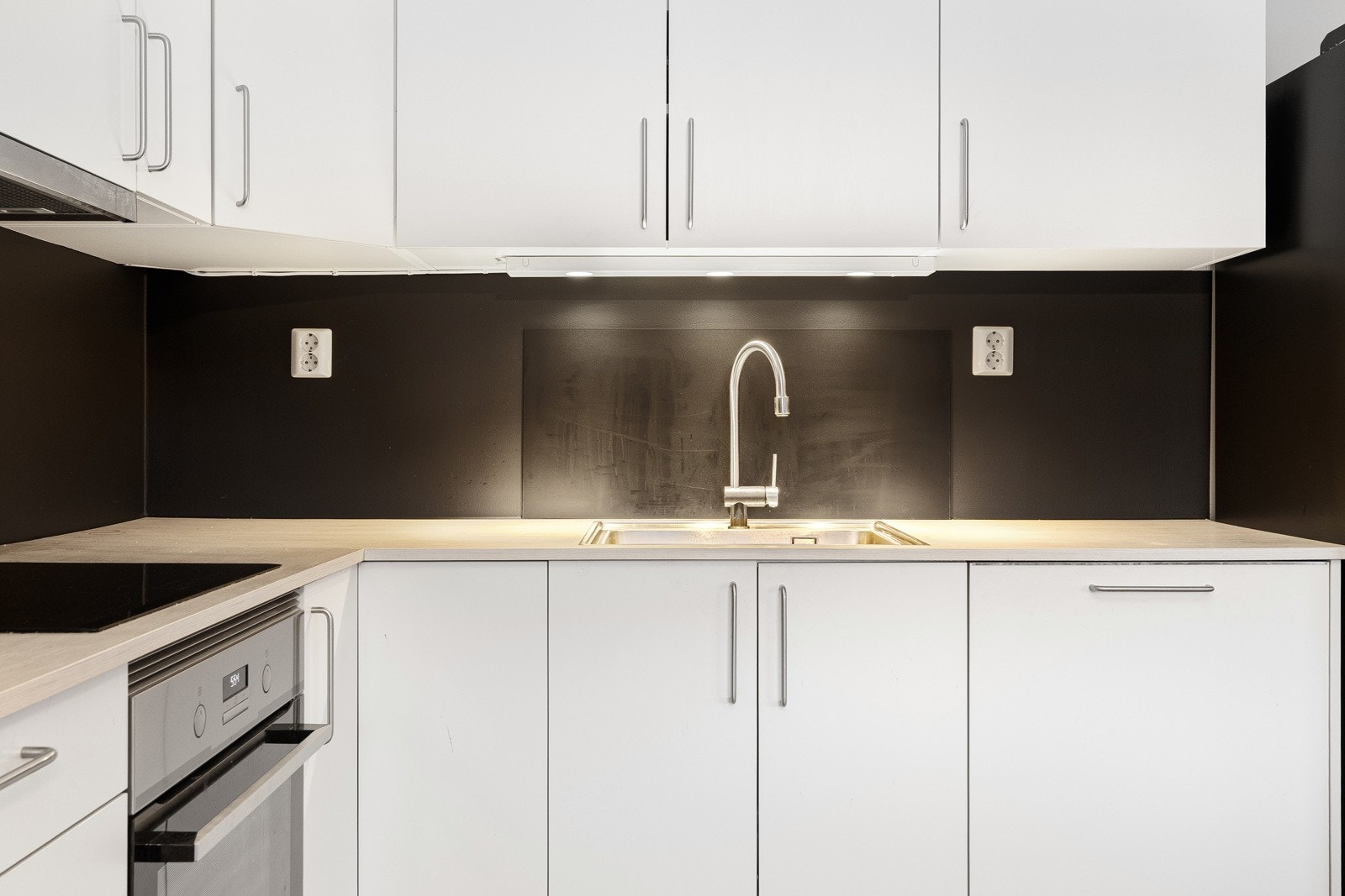 Praktisk kjøkken med integrerte hvitevarer, benkebelysning og kjøkkenventilator i overskap. Funksjonell utforming med normal bruksslitasje. Galleribilde
