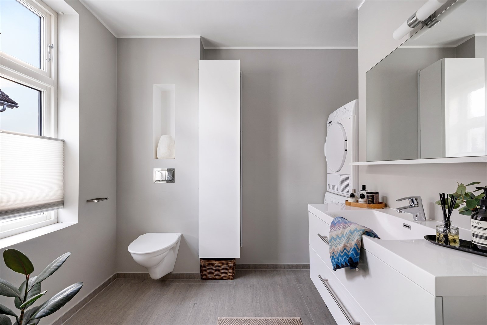 Lyst og moderne bad med stilrent design, plass til hvitevarer og rikelig med oppbevaringsplass. Perfekt for en komfortabel hverdag. Galleribilde