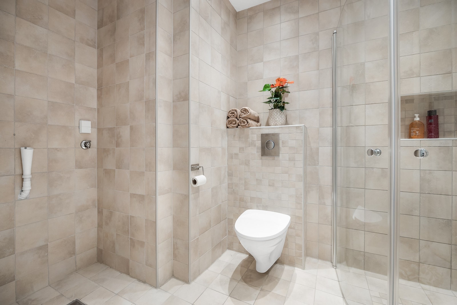 Badet har dusjhjørne med foldedører av glass og opplegg for vaskemaskin Galleribilde