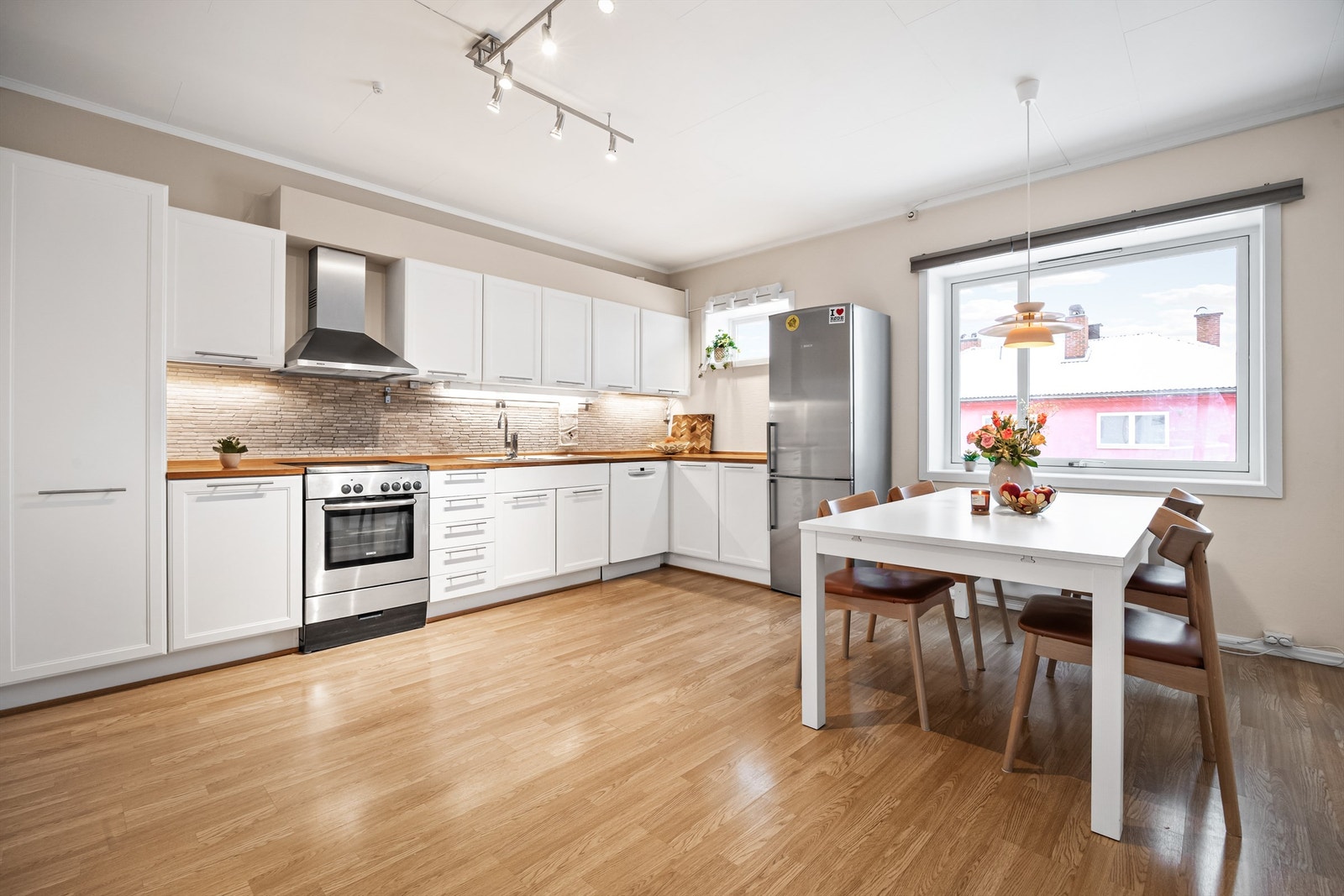 Klassisk og profilert kjøkkeninnredning med over- og underskap samt høyskap i hvit utførelse Galleribilde