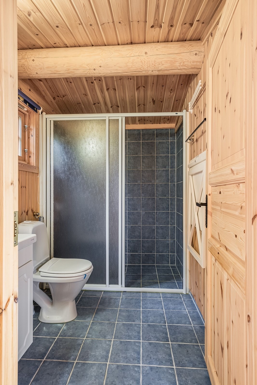 Badet i annekset har flislagte gulv med varmekabler, dusjnisje, servant nedfelt i benkeskap og frittstående toalett. Galleribilde