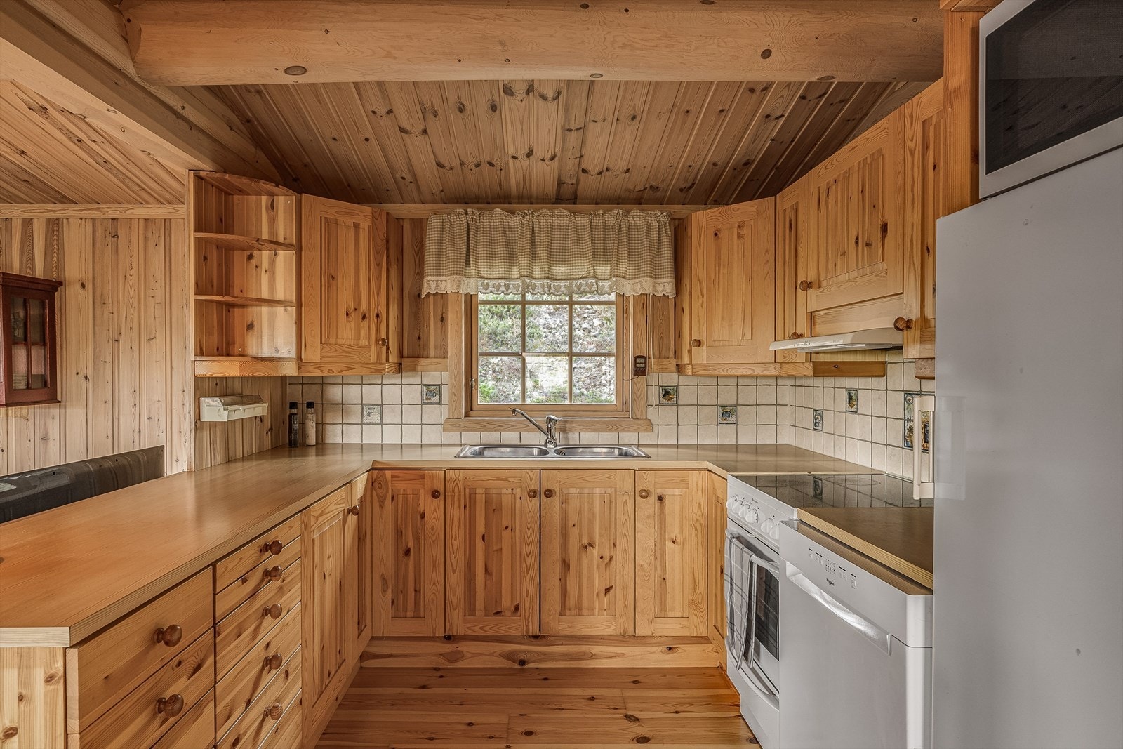 Midt i hytta finner du kjøkkenet, som har heltre innredening med speilfronter og laminerte benkeplater. Kjøkkenet har godt med oppbevaringsplass og romslige arbeidssoner. Hvitevarene medfølger. Galleribilde