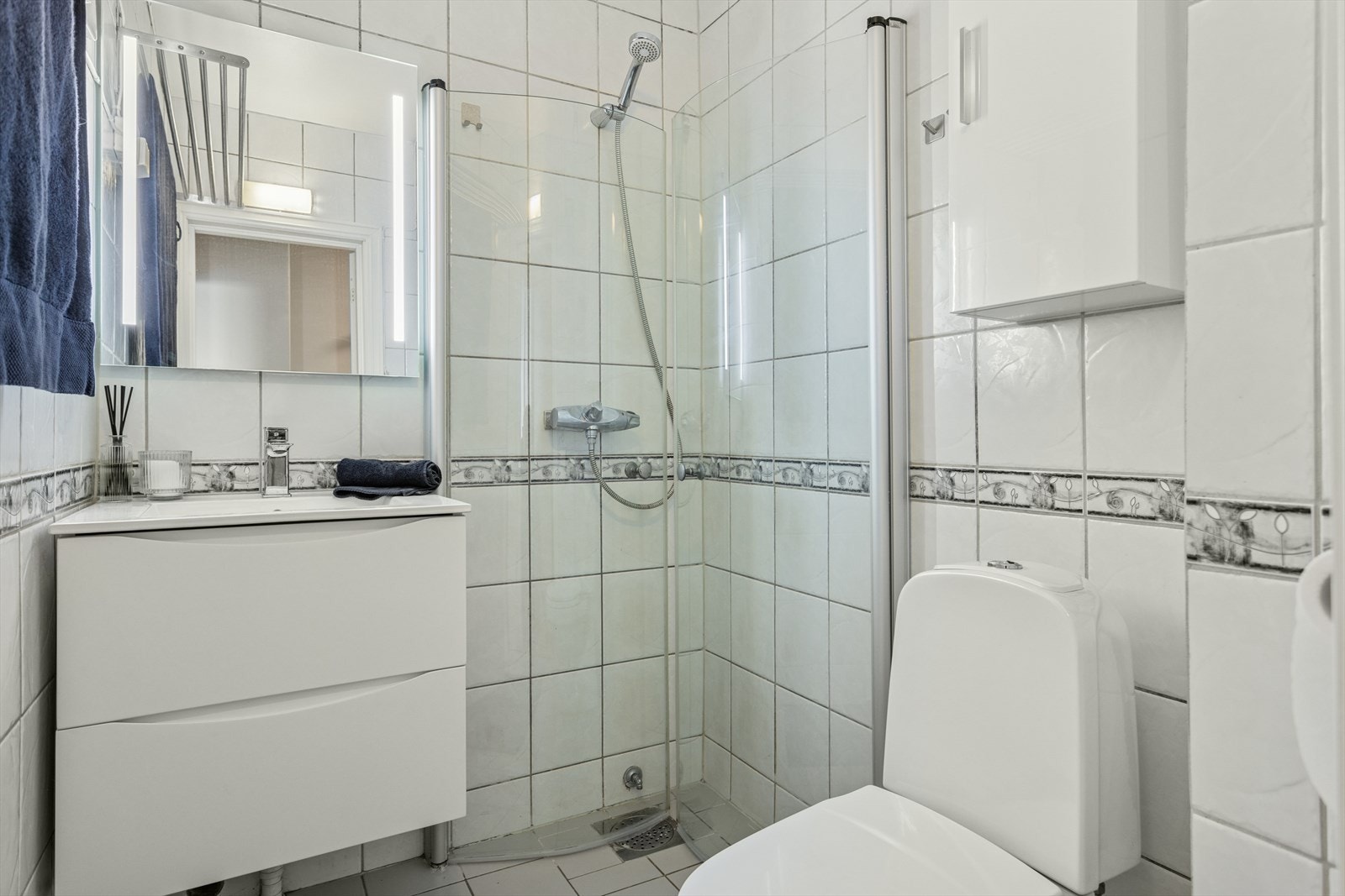 Badet har fliser på vegger og gulv. Baderomsviften, skap, skuffer og speil ble byttet i 2024. Galleribilde