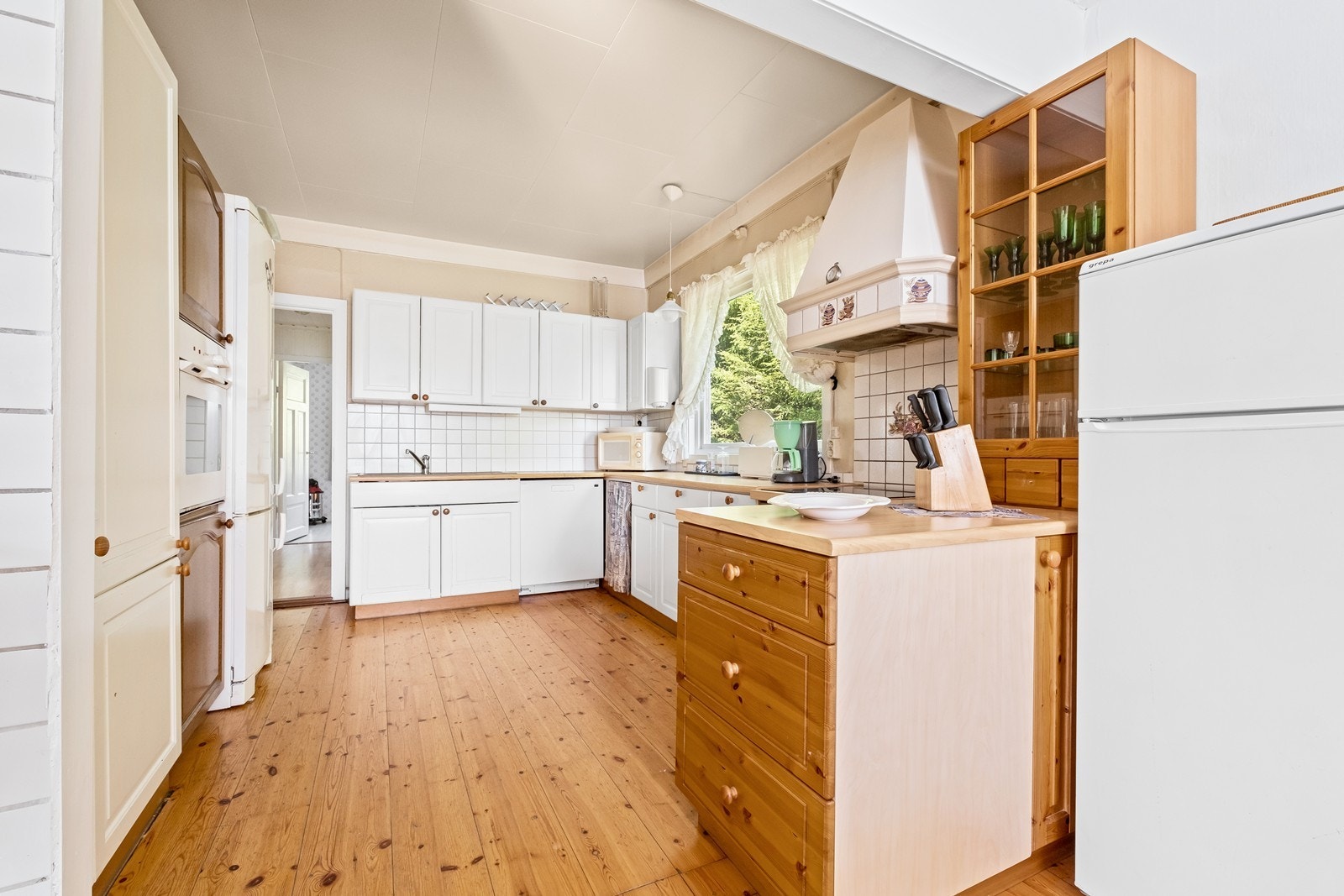 Kjøkkeninnredning med både hvitmalte og furu kjøkkenfronter. Galleribilde