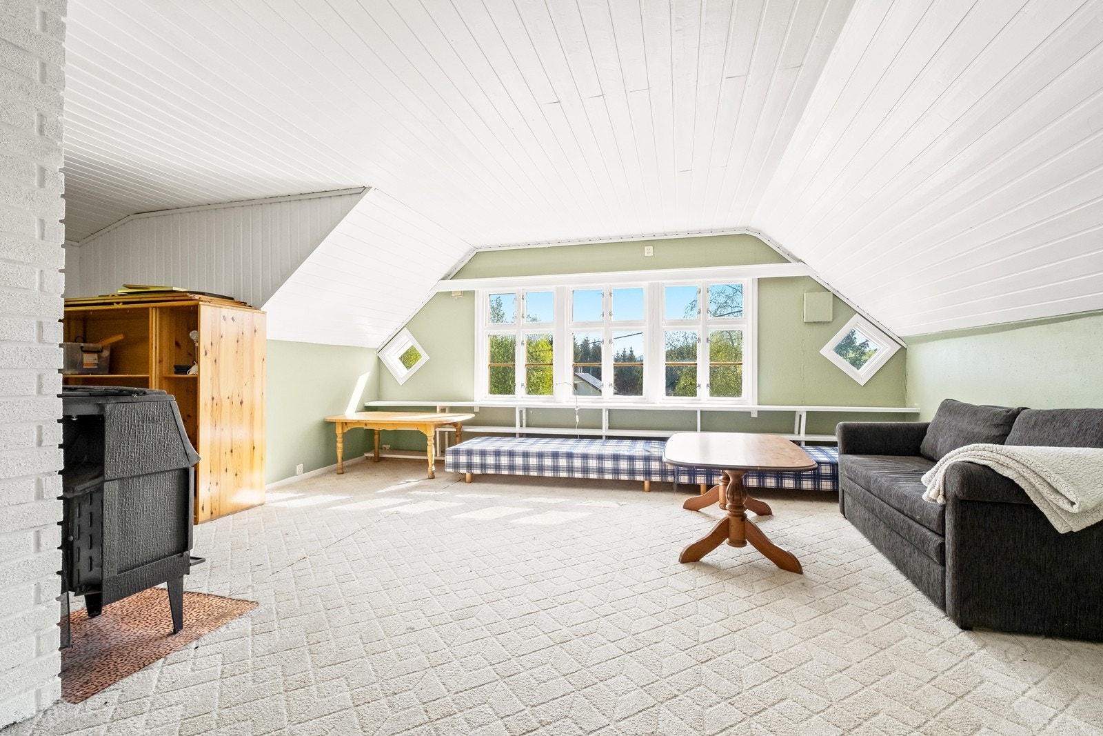 Loftstuen er romslig og lys, med hvitmalt tak, rikt med vinduer og vedovn. Galleribilde