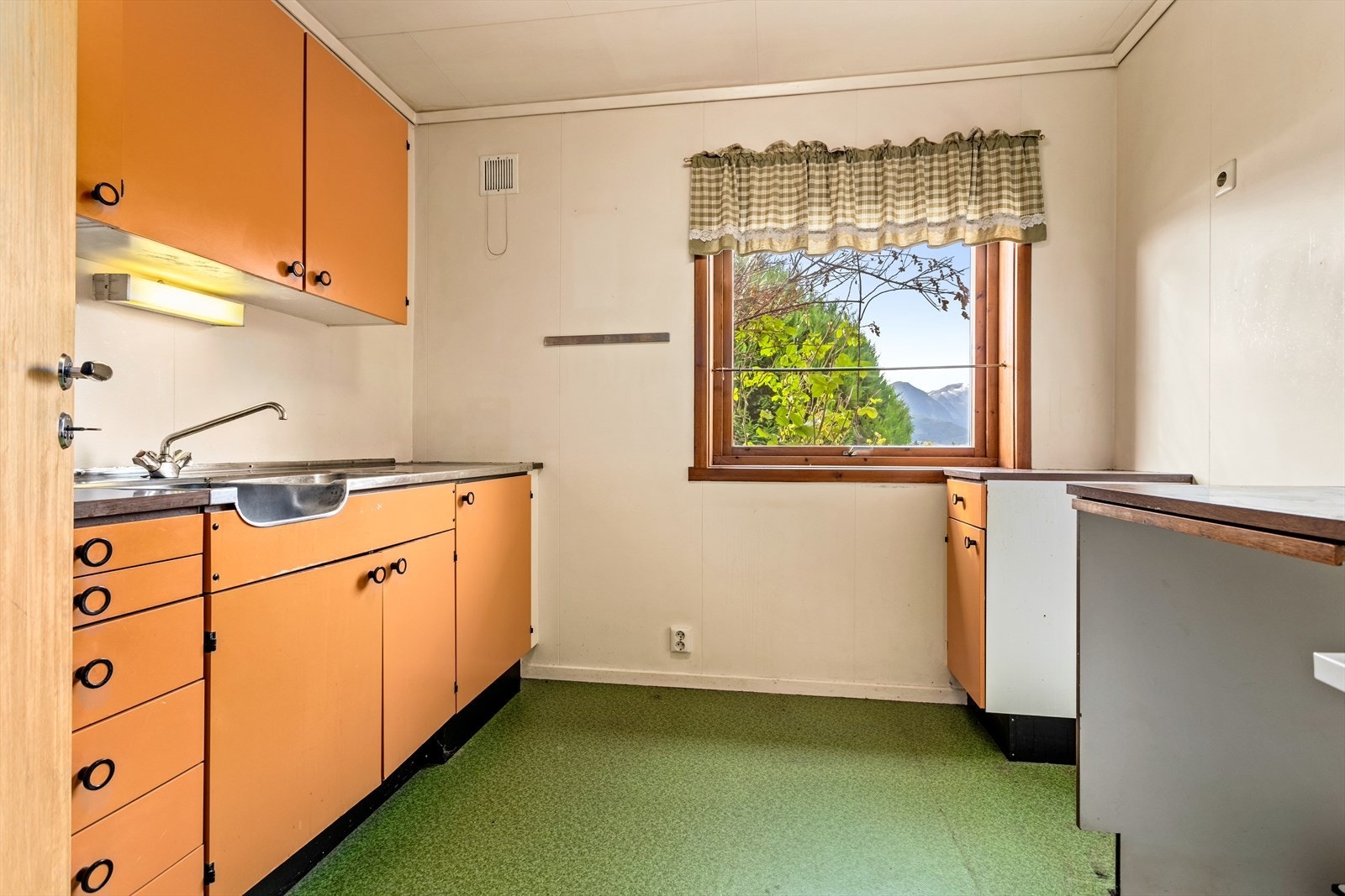 Kjøkkenet har innredning med slette frontar, laminat benkeplate og oppvaskkum i stål. Galleribilde