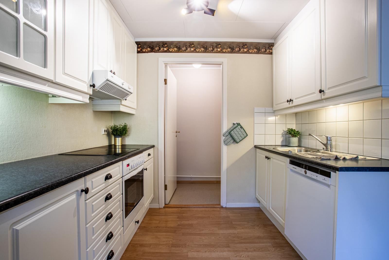 Lyst kjøkken med mye skap og benkeplass. Galleribilde