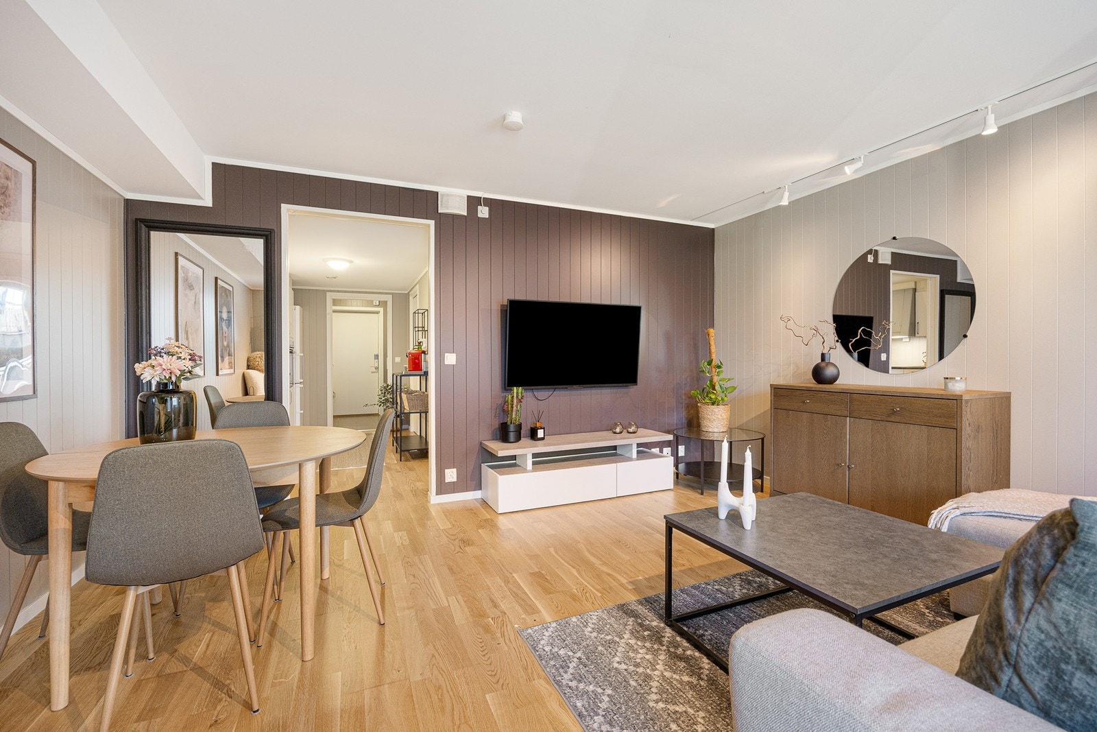 Kjøkkenet glir sømløst over i stuen, og det er fin kontakt mellom sonene. Parkettgulvet er det samme, kombinert med panelplater malt i en mørk jordtone og en dus grånyanse. Galleribilde