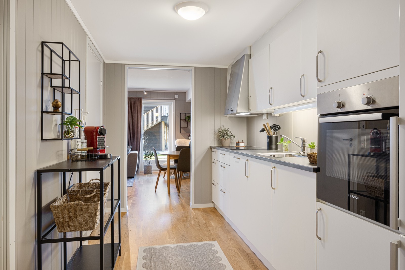 Plassen er godt utnyttet, med skap- og benkeplass på den ene langveggen. Integrert i innredningen finner man platetopp, oppvaskmaskin og stekeovn i høyskap. Galleribilde