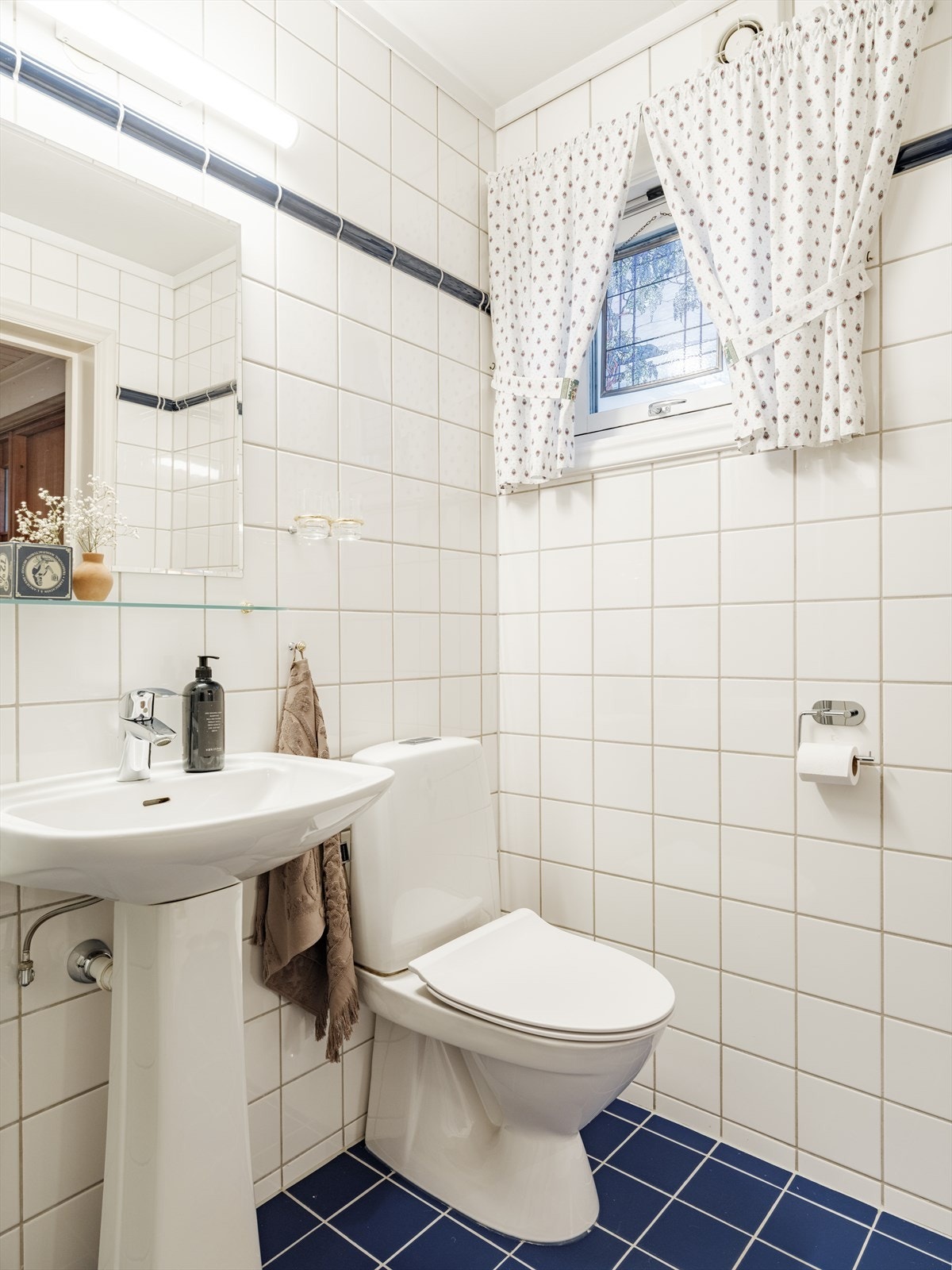 Hoveddelen av boligen har to baderom, ett i 1. etasje og ett i 2. etasje. Badet i 1. etasje er innredet med dusjhjørne, servant og toalett. Galleribilde