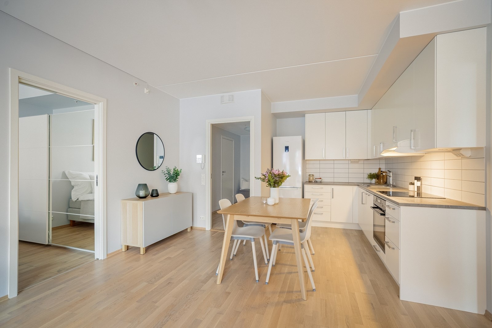 Flott kjøkken fra Drømmekjøkken. Lys innredning fra byggeår med glatte fronter, fliser på vegg over kjøkkenbenken og benkeplate i laminat. Galleribilde