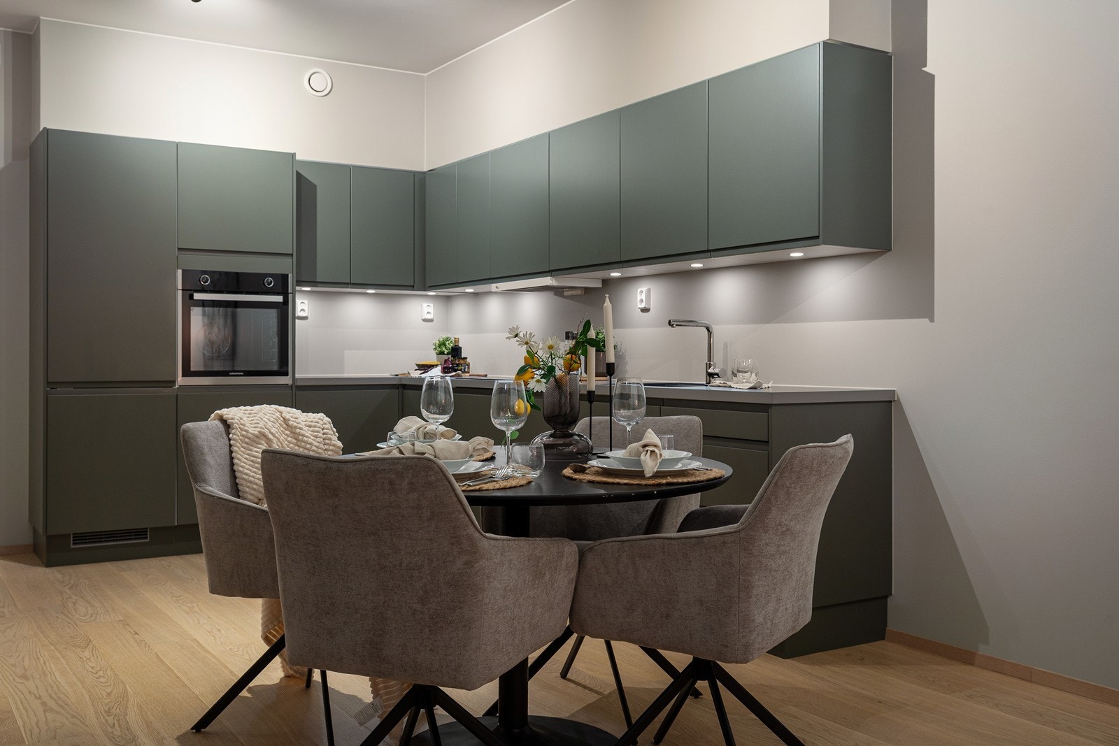 Kjøkkeninnredningen har et moderne uttrykk med slette, mørkegrønne fronter. Galleribilde