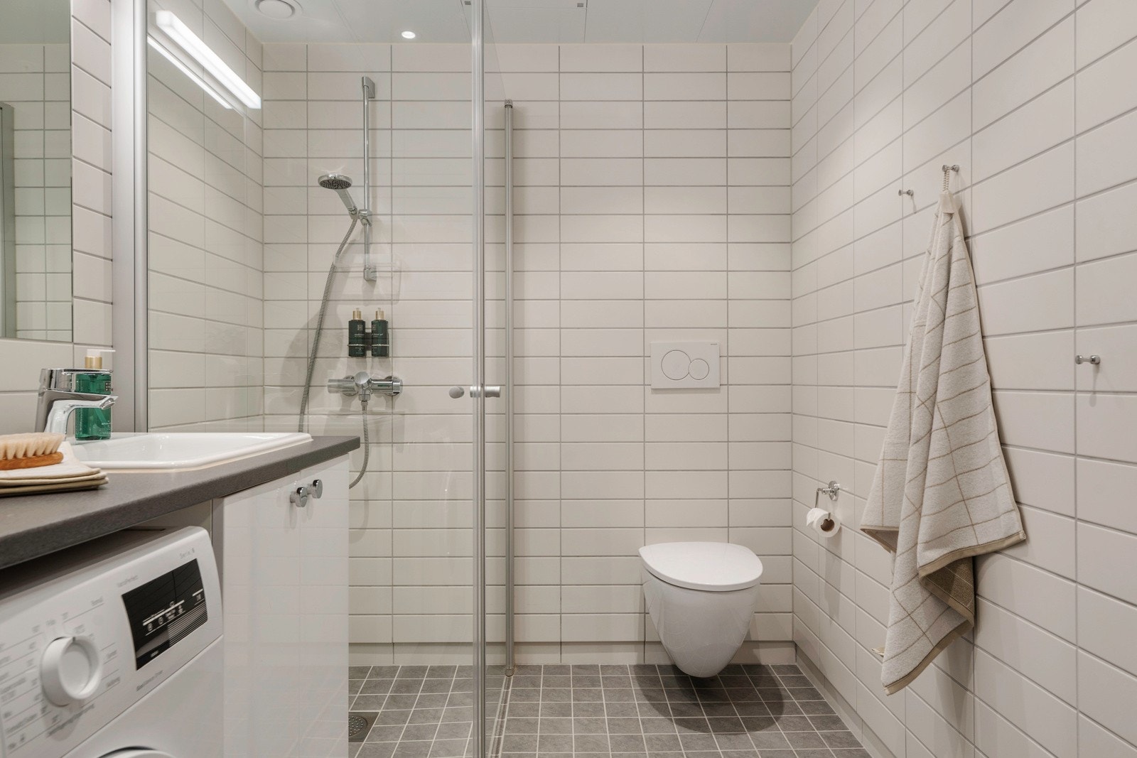 Stilrent bad, innredet med servantinnredning m/ vaskemaskin, vegghengt toalett, dusjhjørne. Flislagt gulv med varme. Galleribilde