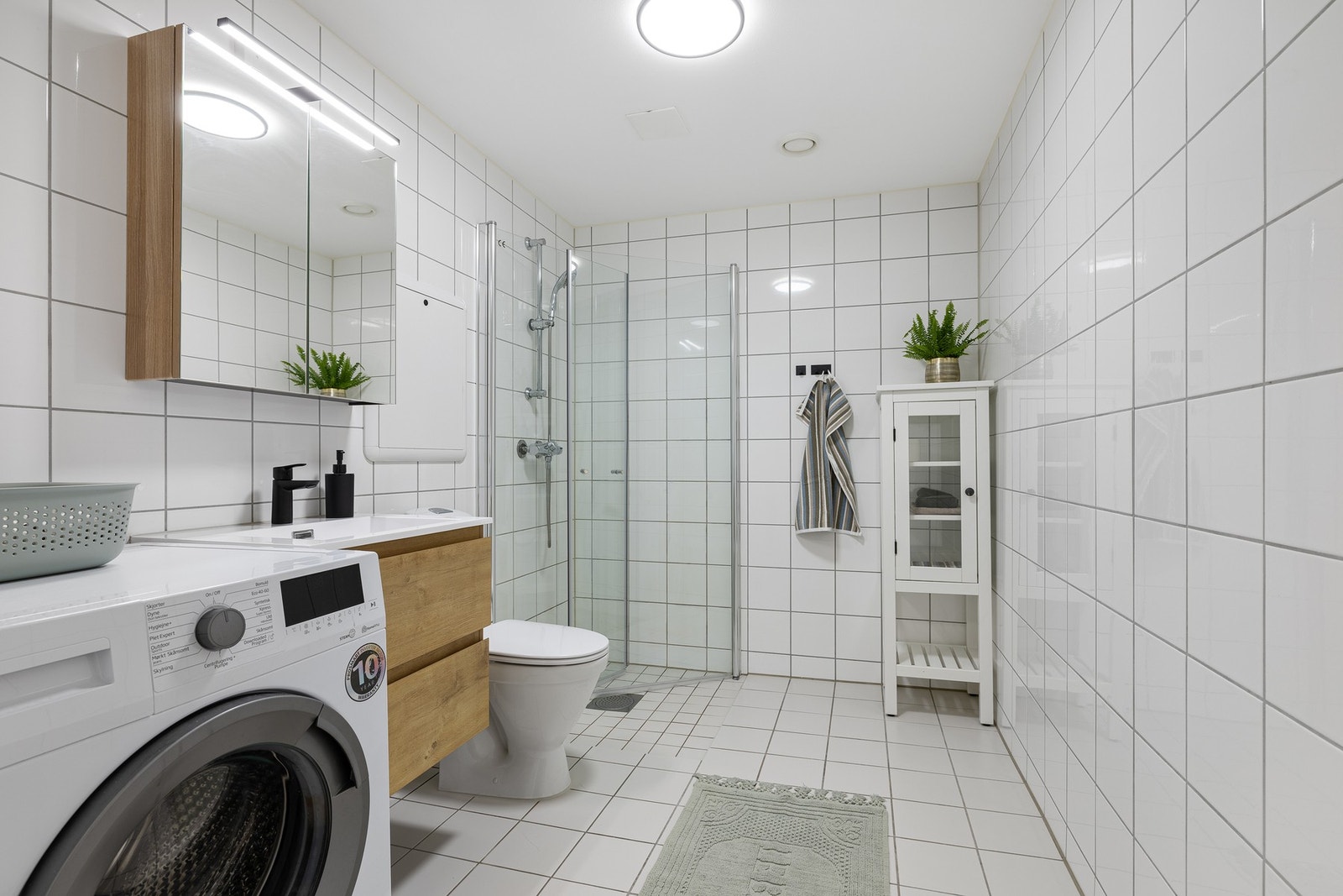 Det flislagte badet er utstyrt med varmekabler og opplegg for vaskemaskin Galleribilde