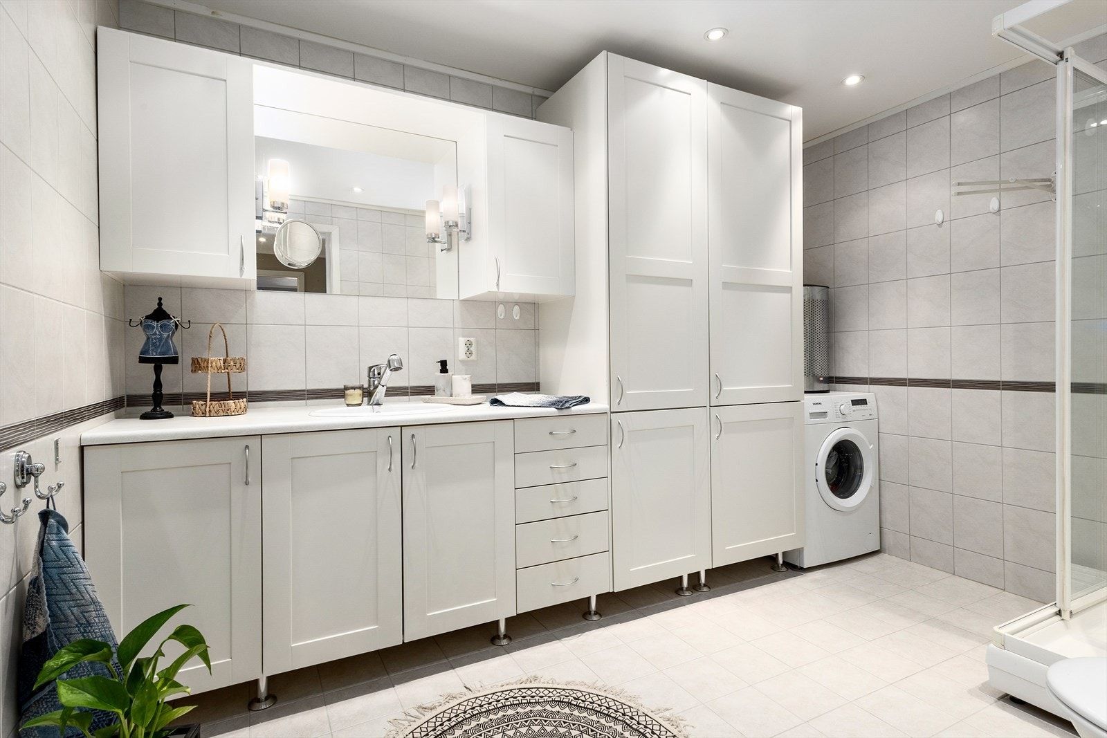 Badet er svært godt utnyttet med god innredning og funksjonelle løsninger. Her er det plass til vaskemaskin og tørketrommel, slik at rommet også fungerer som vaskerom - praktisk og plassbesparende. Galleribilde