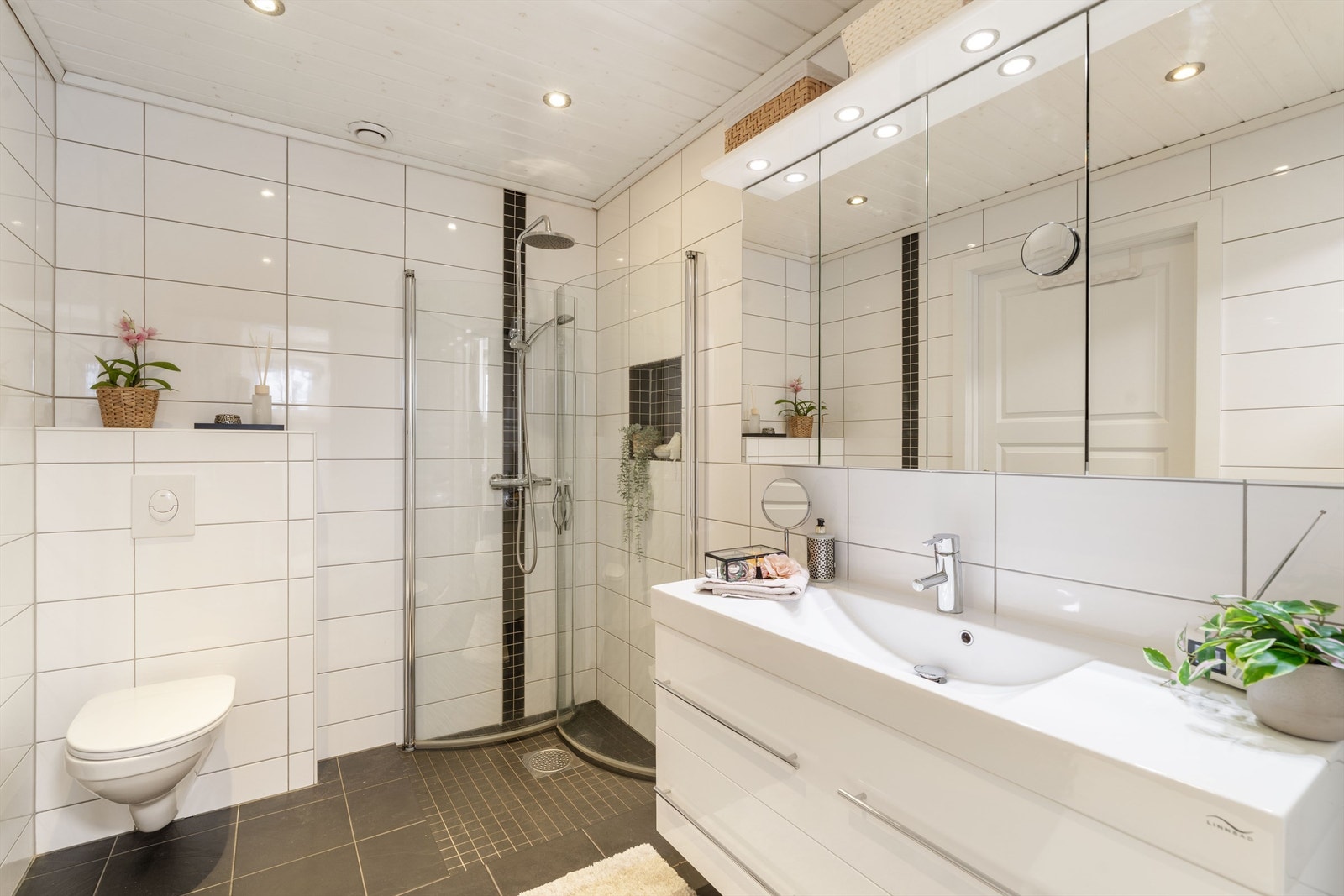 Badet har flislagt gulv med gulvvarme, flislagte vegger og vegghengt toalett. Galleribilde