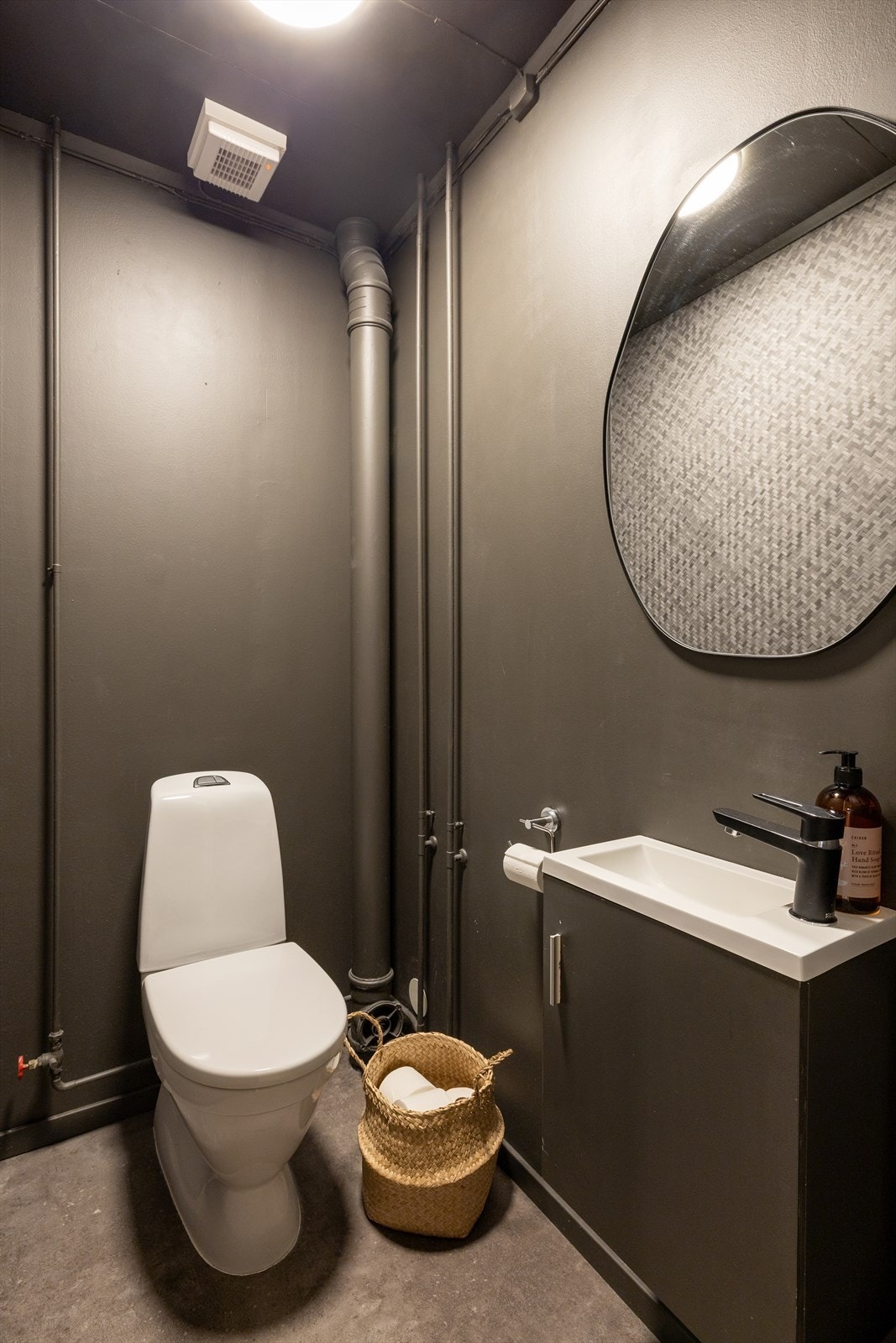 Separat toalettrom med gulvstående toalett og en enkel servant med tilhørende innredning. Galleribilde