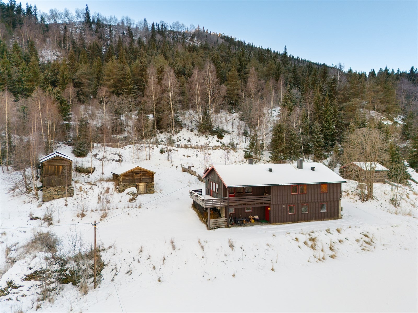 Tunet er opparbeidet med grøntarealer, mens resten av tomten består av åpent terreng og trær/skog. Galleribilde