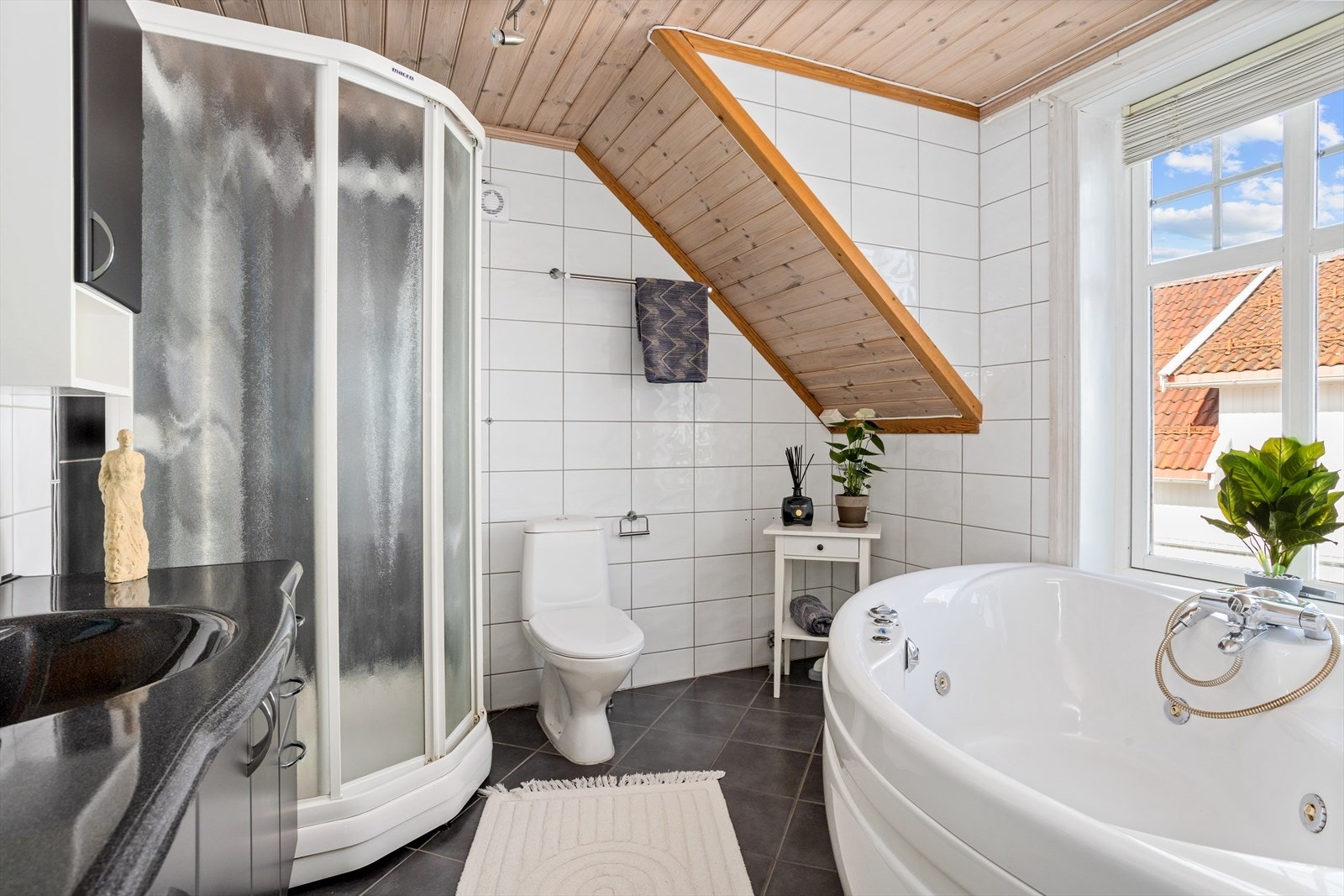 Pent flislagt bad med gulvvarme. Baderomsinnredningen består av dusjkabinett, boblekar og toalett, samt opplegg for vaskemaskin i hjørnet av badet. Galleribilde