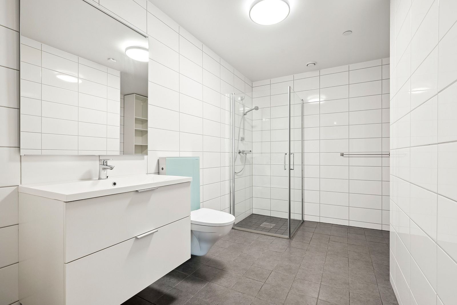 Flislagt bad med varmekabler. Innredning med skuffer. Opplegg for vaskemaskin. Galleribilde