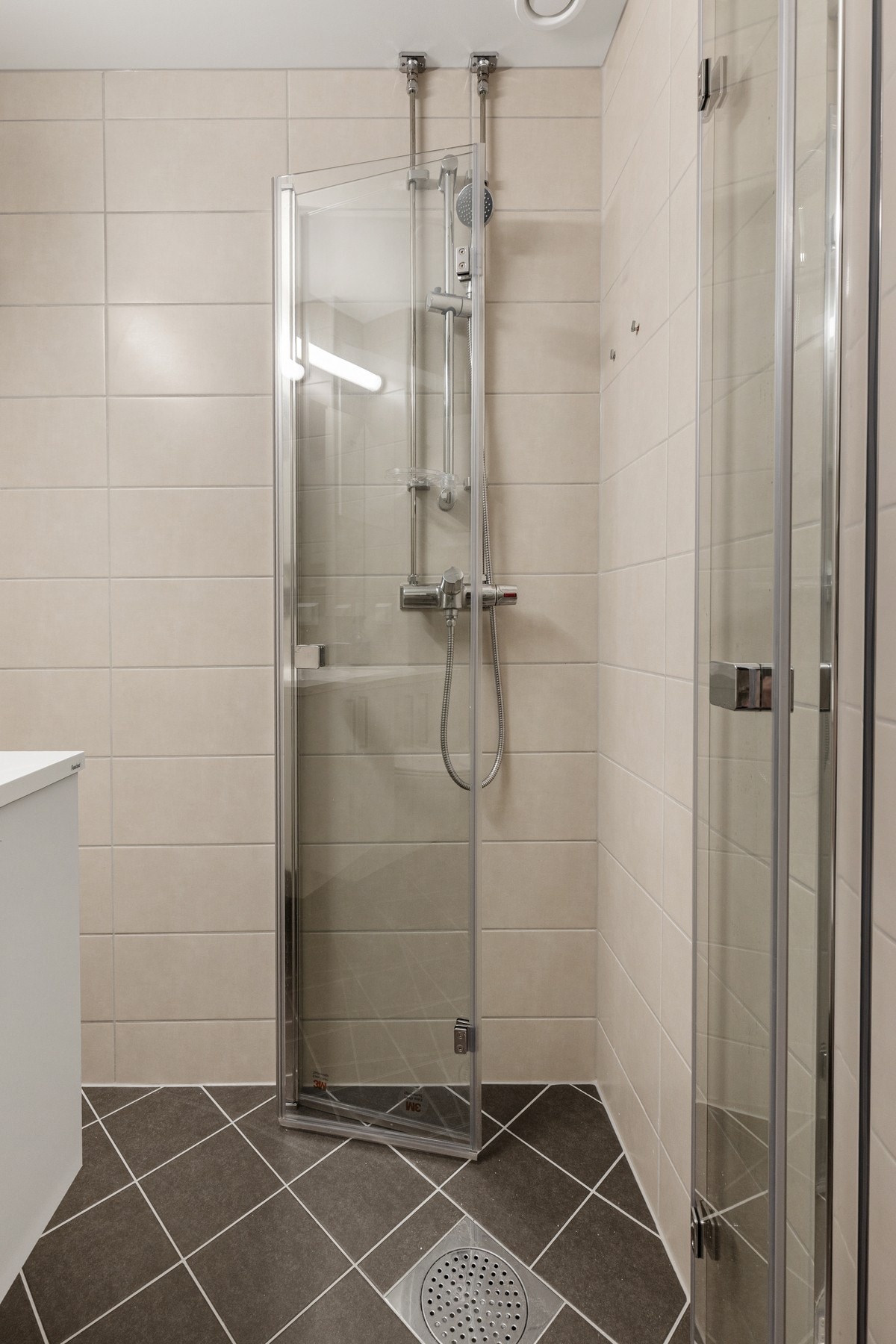 Det har servant med glatte fronter, vegghengt toalett og et praktisk dusjhjørne med to foldbare glassdører. Det er også tilrettelagt for vaskemaskin. Galleribilde