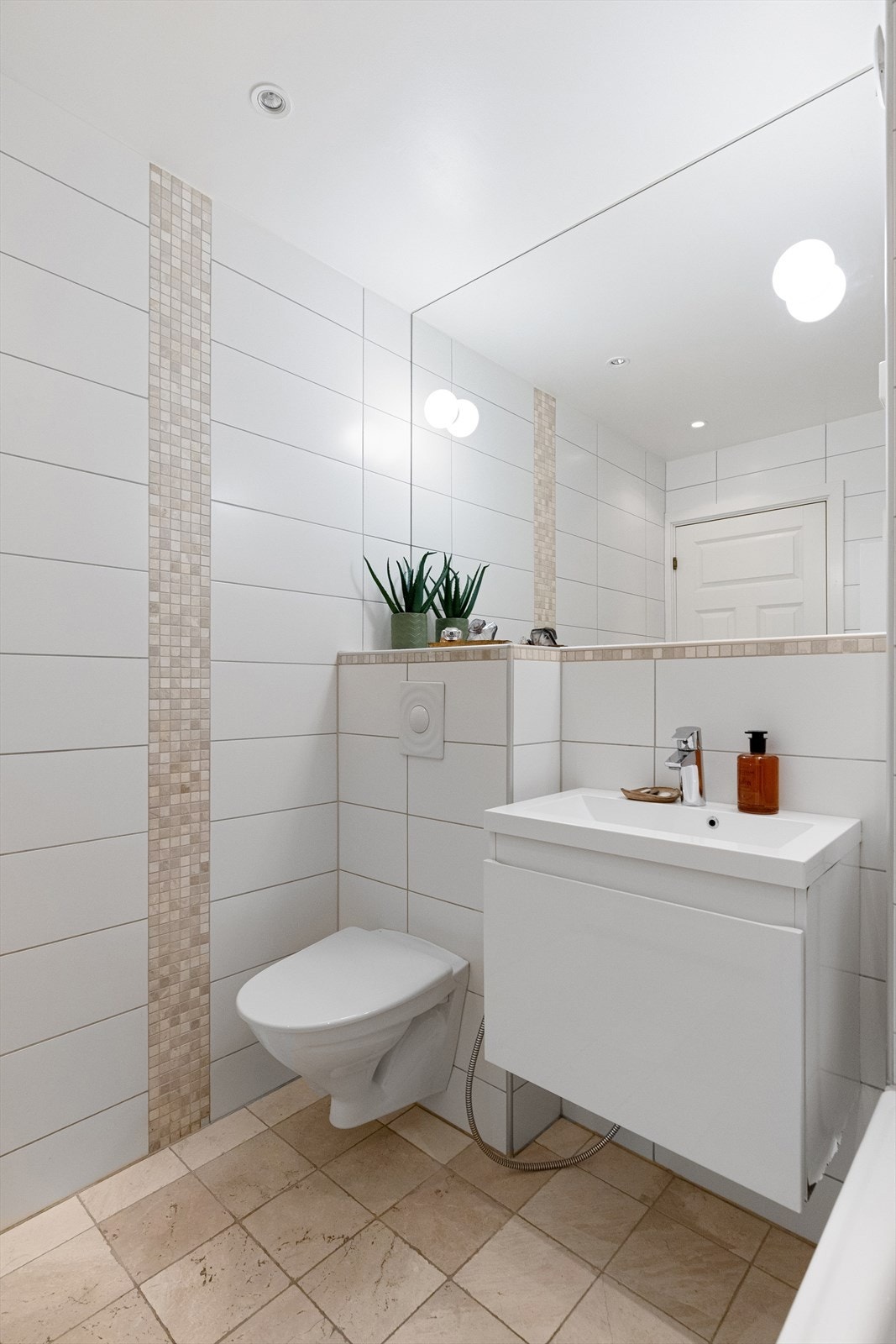 Rommet er innredet med vegghengt toalett med hånddusj, servantmøblement og badekar med hånddusj. Galleribilde