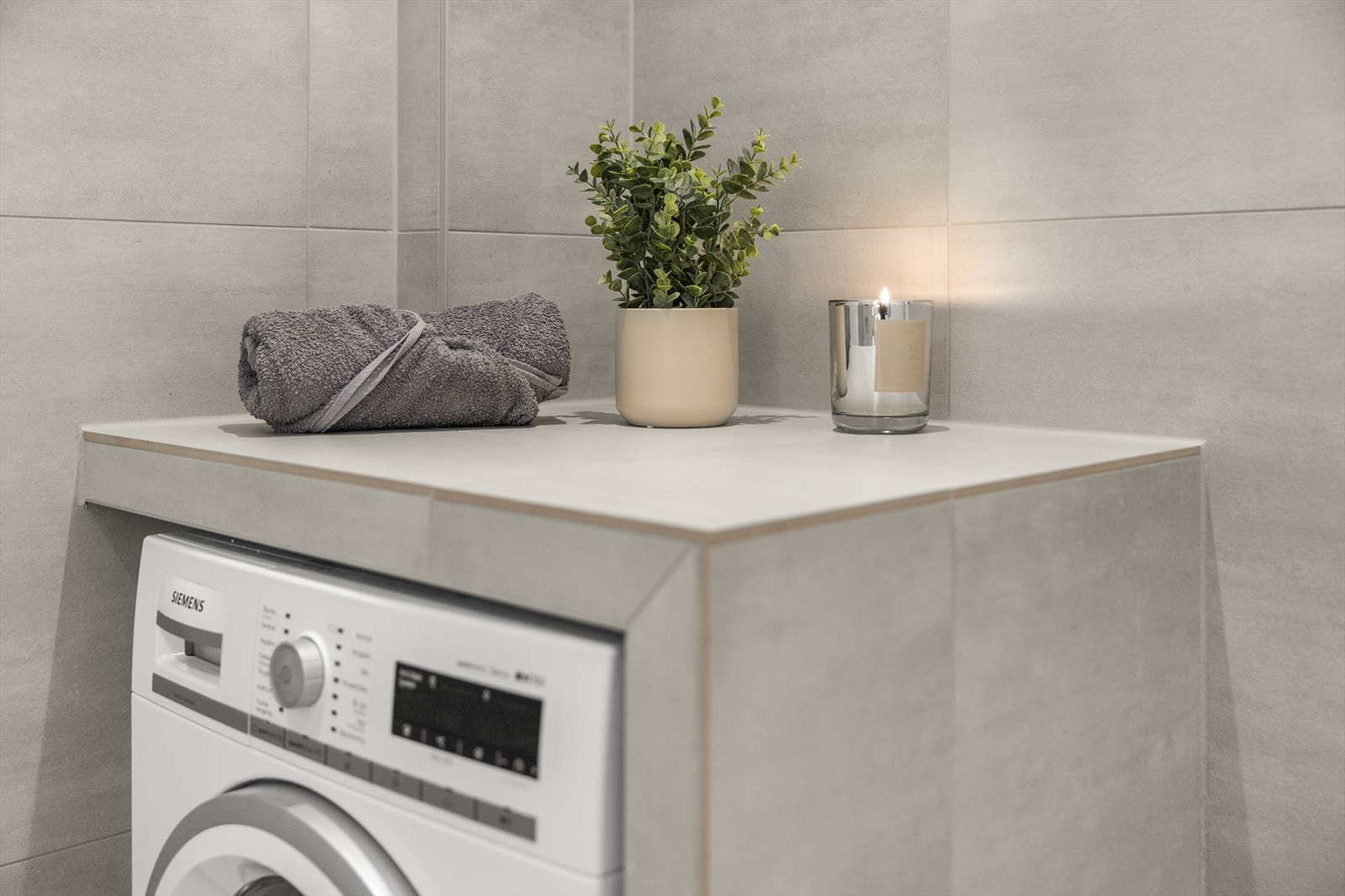 Praktisk og pen løsning for vaskemaskin. Store fliser på gulv og vegger gir en god romfølelse. Galleribilde