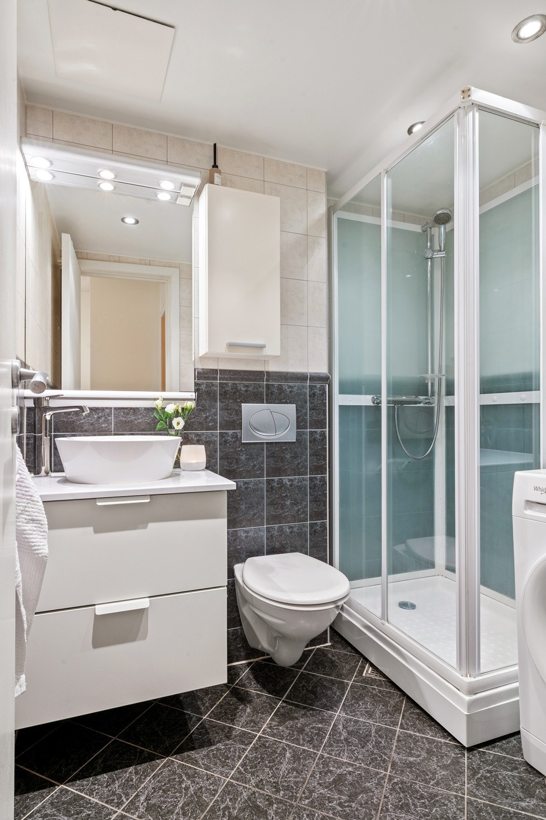 Flislagt bad med dusjkabinett, servant med underskap og opplegg for vaskemaskin. Galleribilde