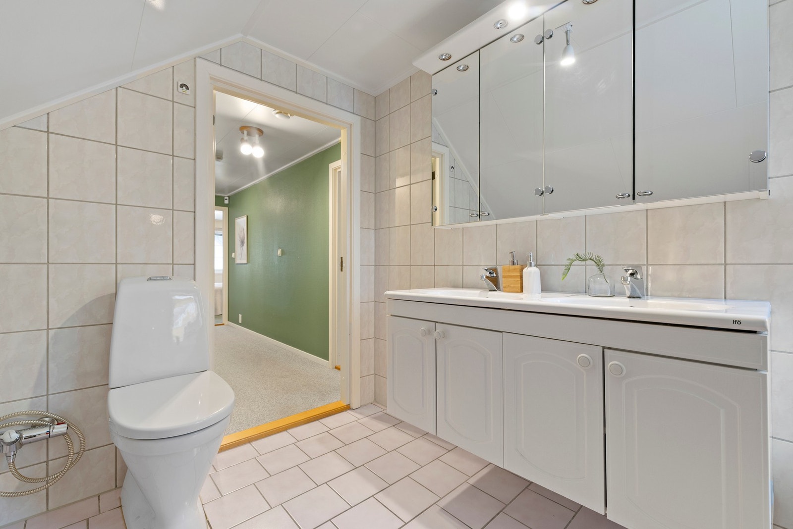 Rommet er utstyrt med dobbeltservant med profilerte fronter, gulvstående toalett og badekar Galleribilde