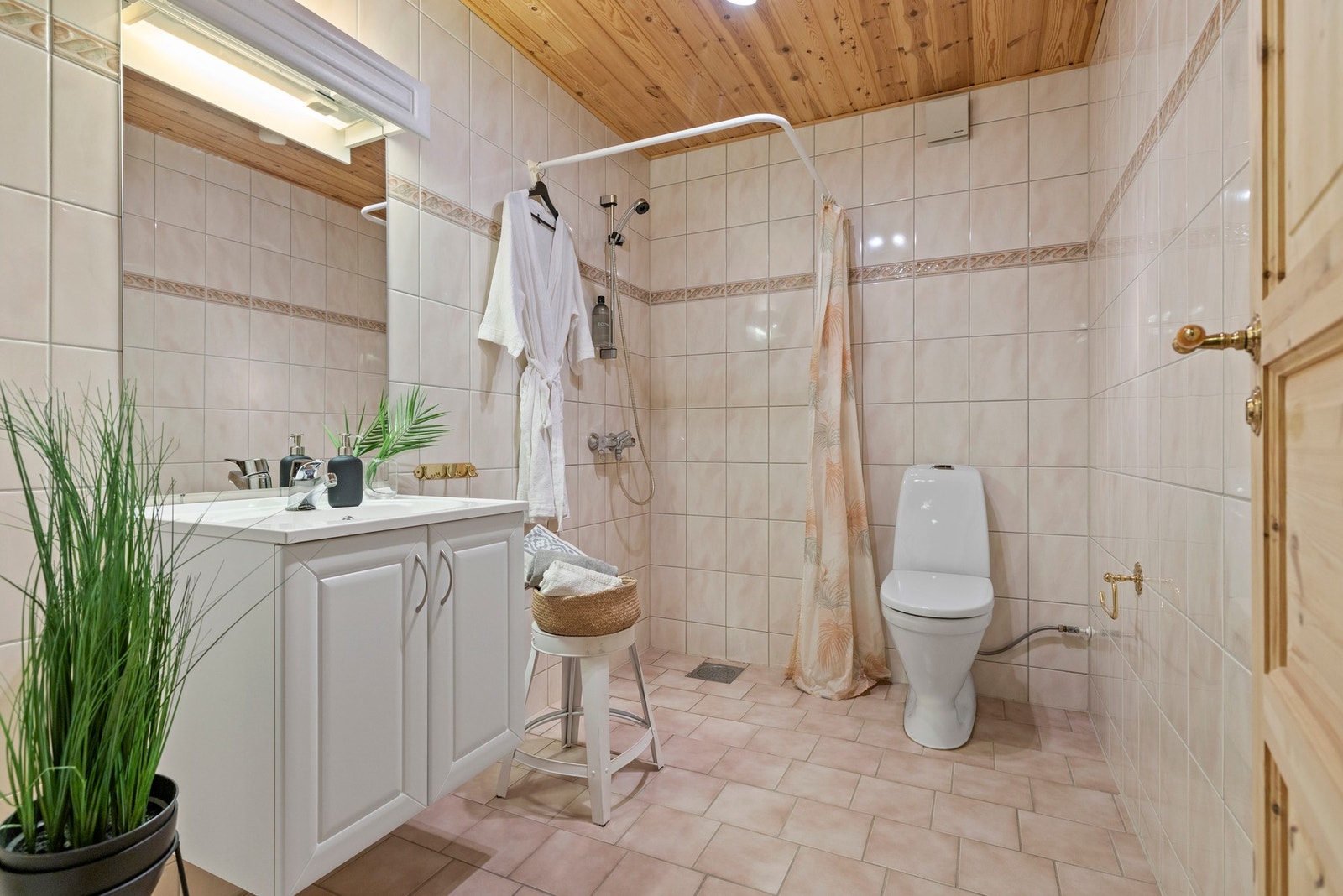 Badet i underetasjen har fliser på gulv og vegger, servant med profilerte fronter, gulvstående toalett og dusjhjørnet Galleribilde