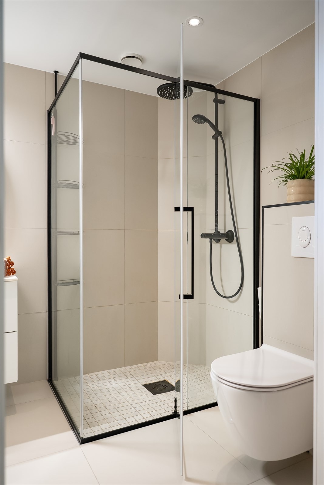 Romslig hjørnedusj i glass med regnfallsdusj og sorte detaljer. Galleribilde