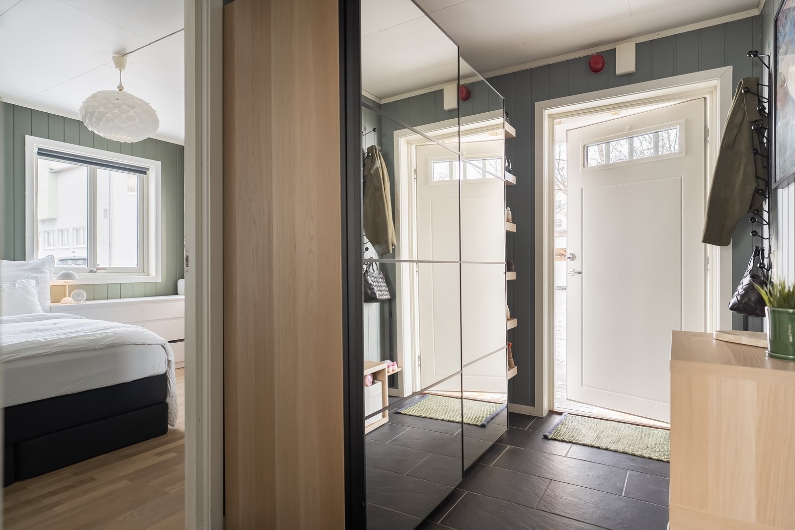 Praktisk adskilt flislagt entré på 5,6 m². Her er det god oppbevaringsplass for klær og sko i praktisk skyvedørsgarderobe med speil. Galleribilde