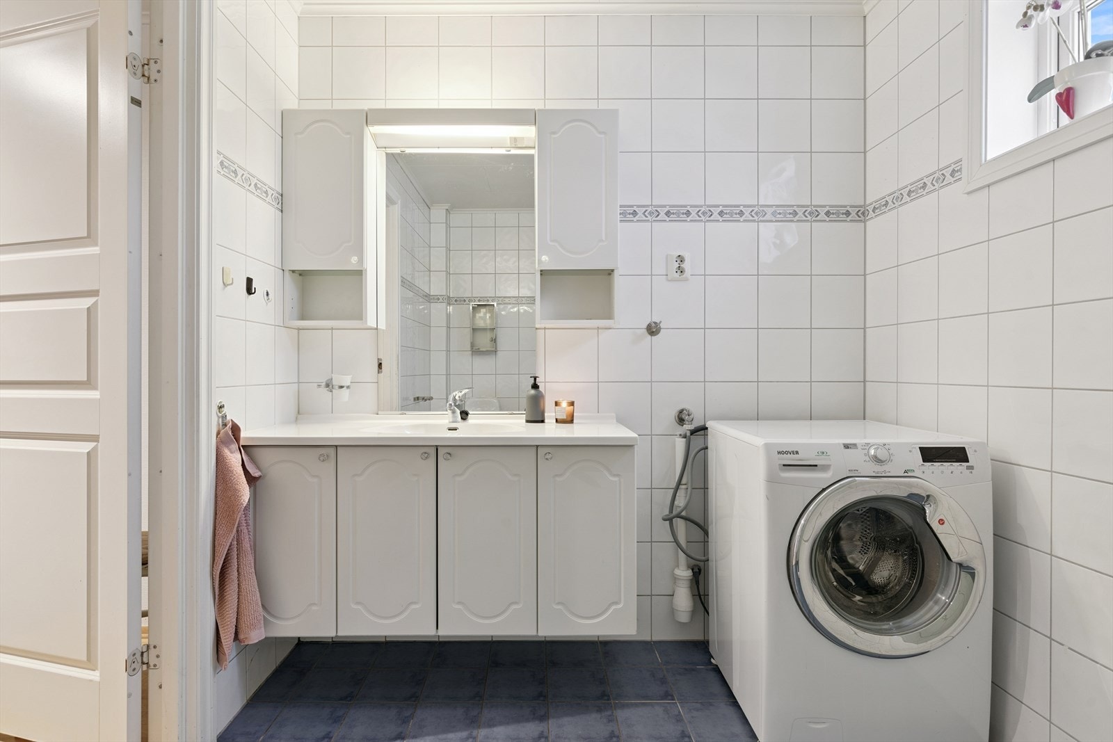 Det er et romslig bad med dusjhjørne og praktisk opplegg for vaskemaskin og tørketrommel. Galleribilde