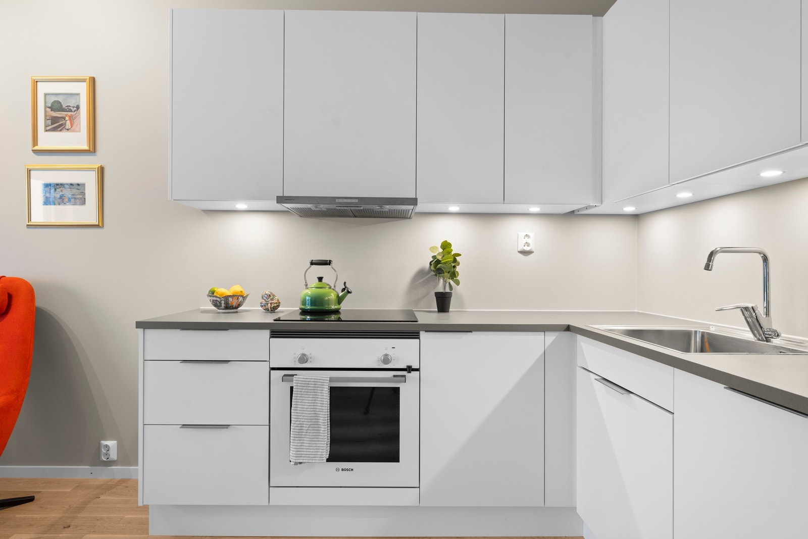 Moderne glatte fronter i klassisk hvit, stilige stål-håndtak og en praktisk benkeplate i grå laminat. Galleribilde