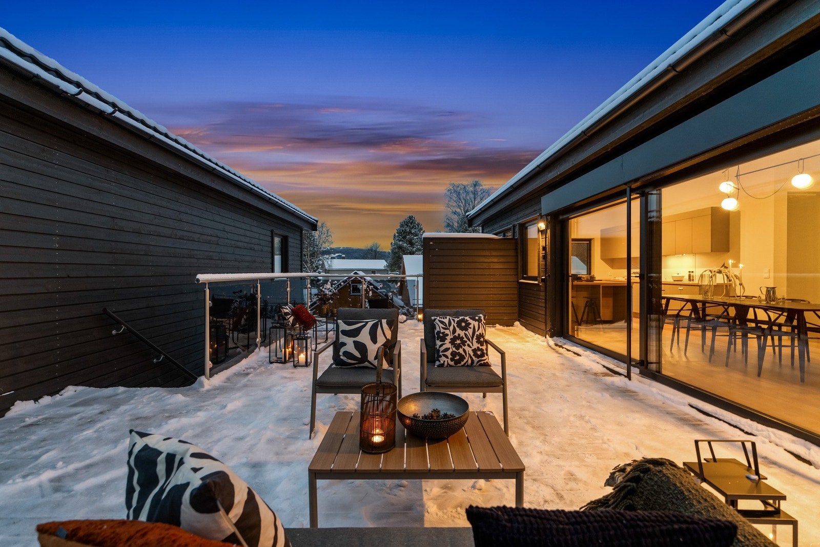 Terrassen er utstyrt med stilrent glassrekkverk, levegg for skjerming og trapp med enkel adkomst til hagen - ideelt for både rolige morgenstunder og sosiale sammenkomster utendørs. Galleribilde