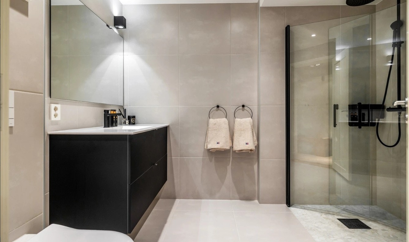 Pent flislagt bad med varme i gulv. Det er et skap til høyre på badet hvor vaskemaskin kommer Galleribilde