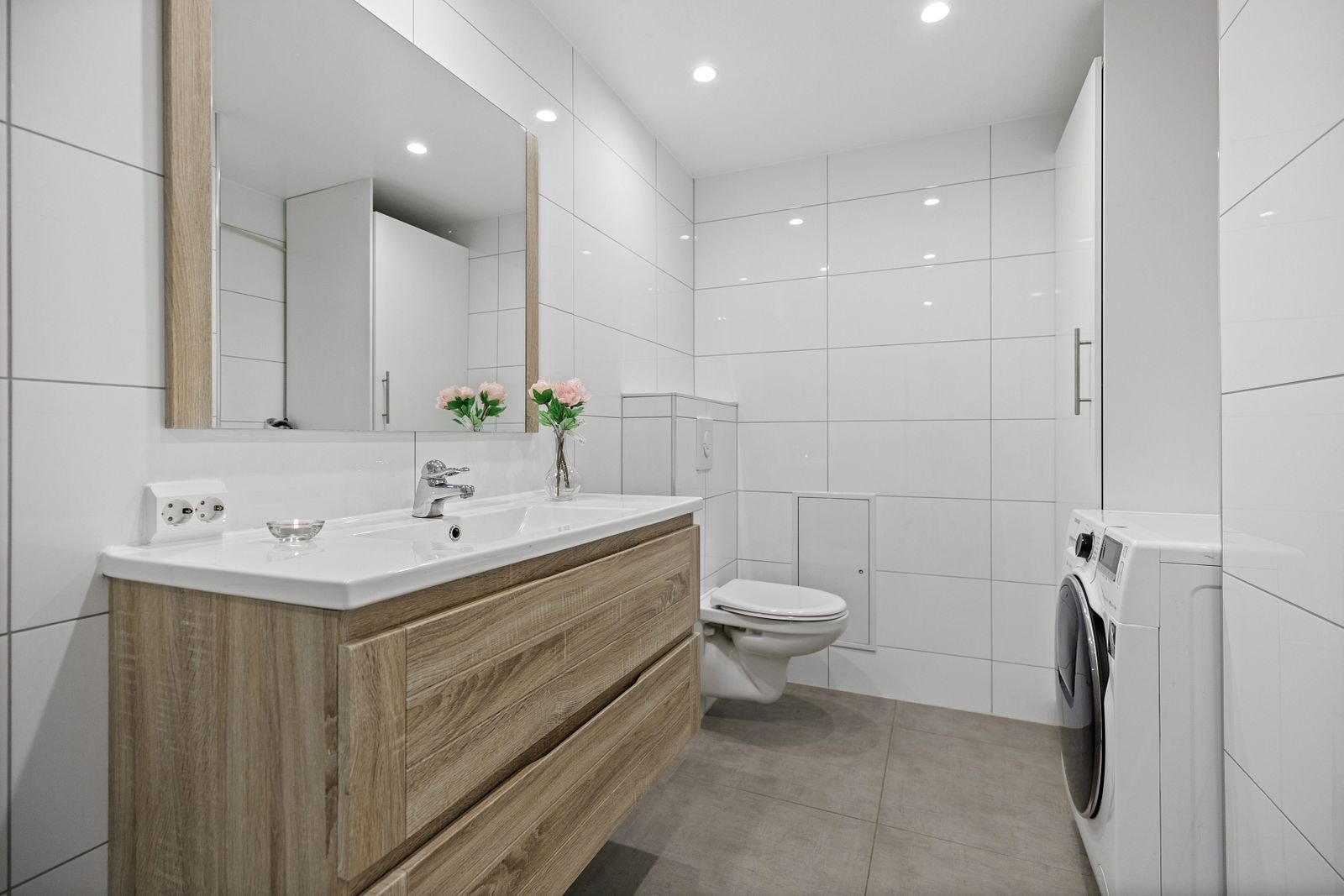 Badet er utstyrt med vegghengt toalett, dusjhjørne, innredning med heldekkende servant. Her det opplegg for vaskemaskin og skap med plass til diverse oppbevaring. Galleribilde