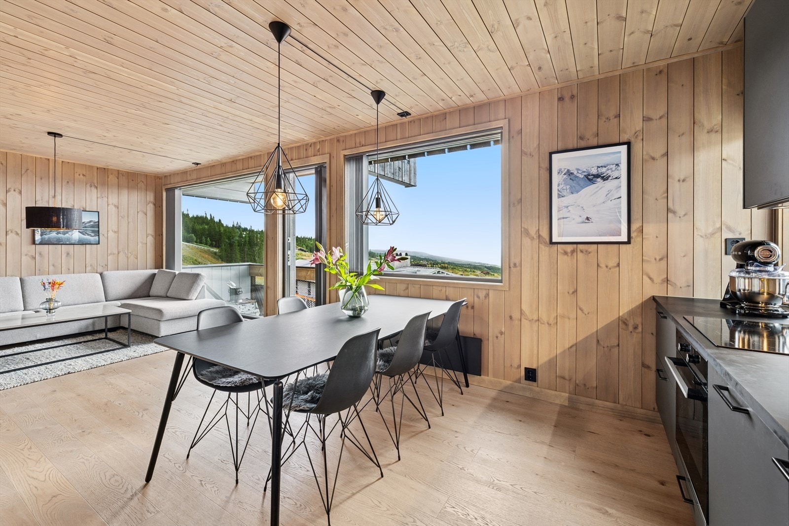 Den åpne løsningen gir god flyt mellom kjøkken og stue, og store vinduer slipper inn rikelig med lys Galleribilde