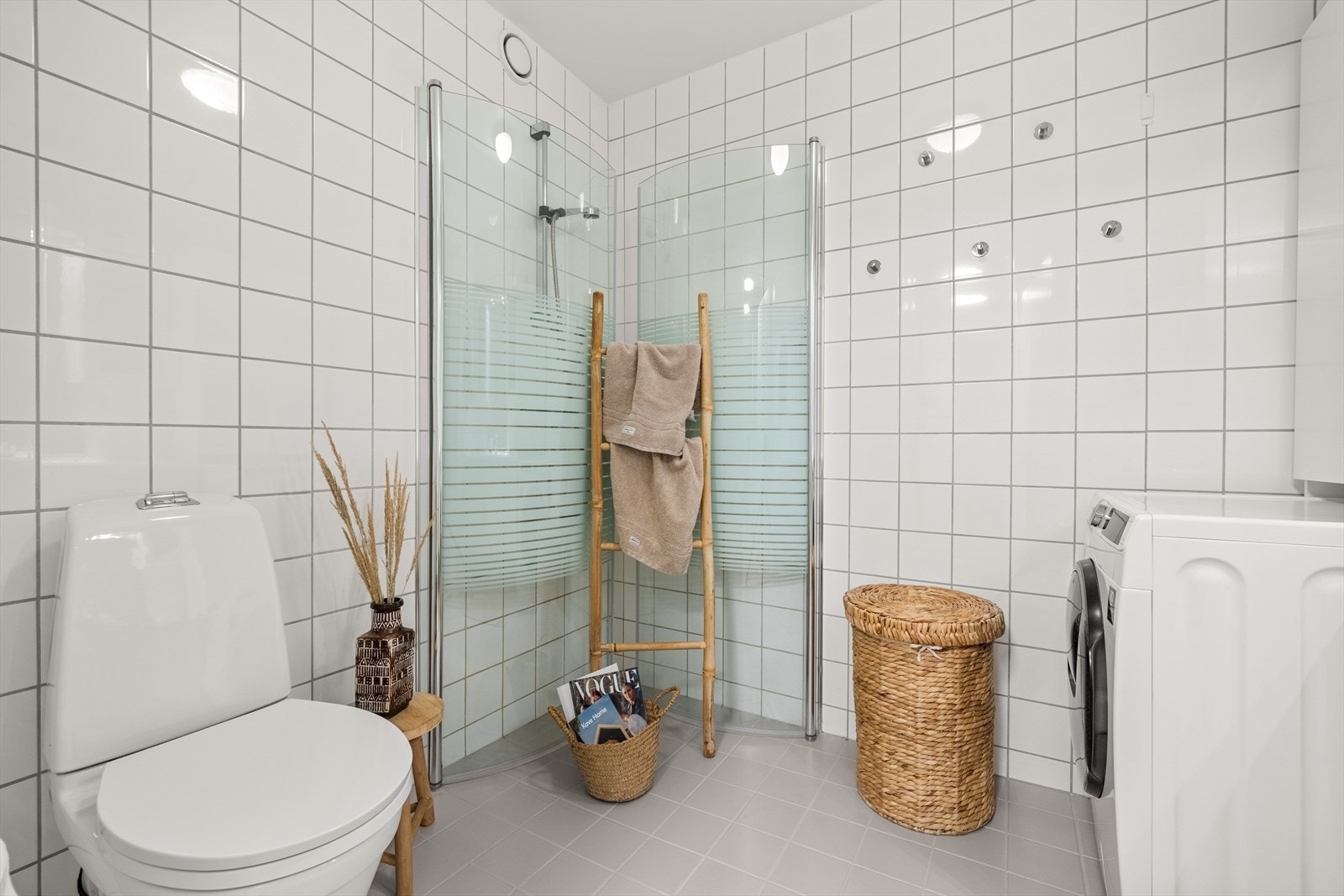 Badet er utstyrt med servant med underskap, veggskap og speil med lys, dusjnisje med innfellbare glassdører, og gulvmontert toalett Galleribilde