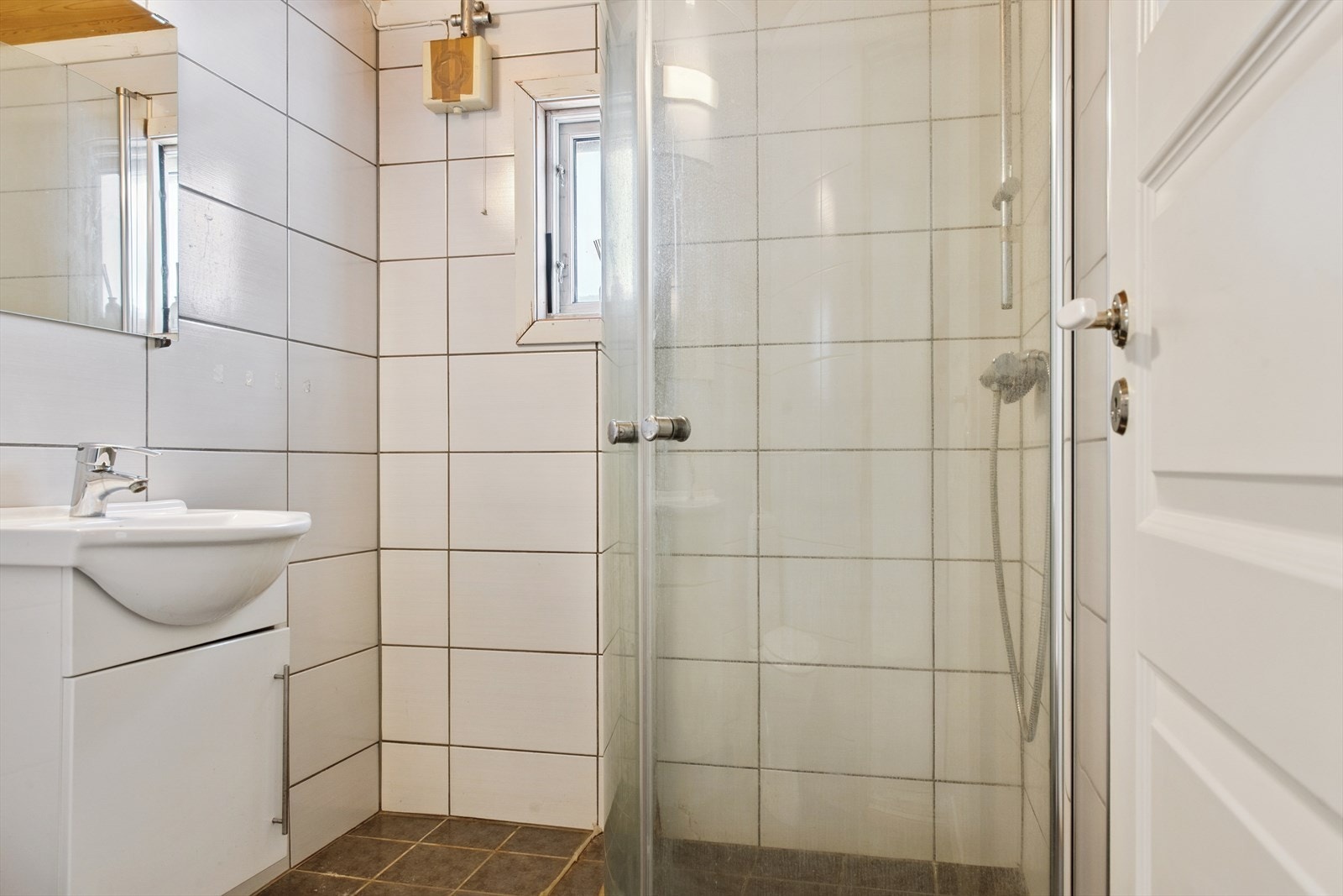 Flislagt bad med liten innredning med servant, toalett, dusjkabinett. Galleribilde