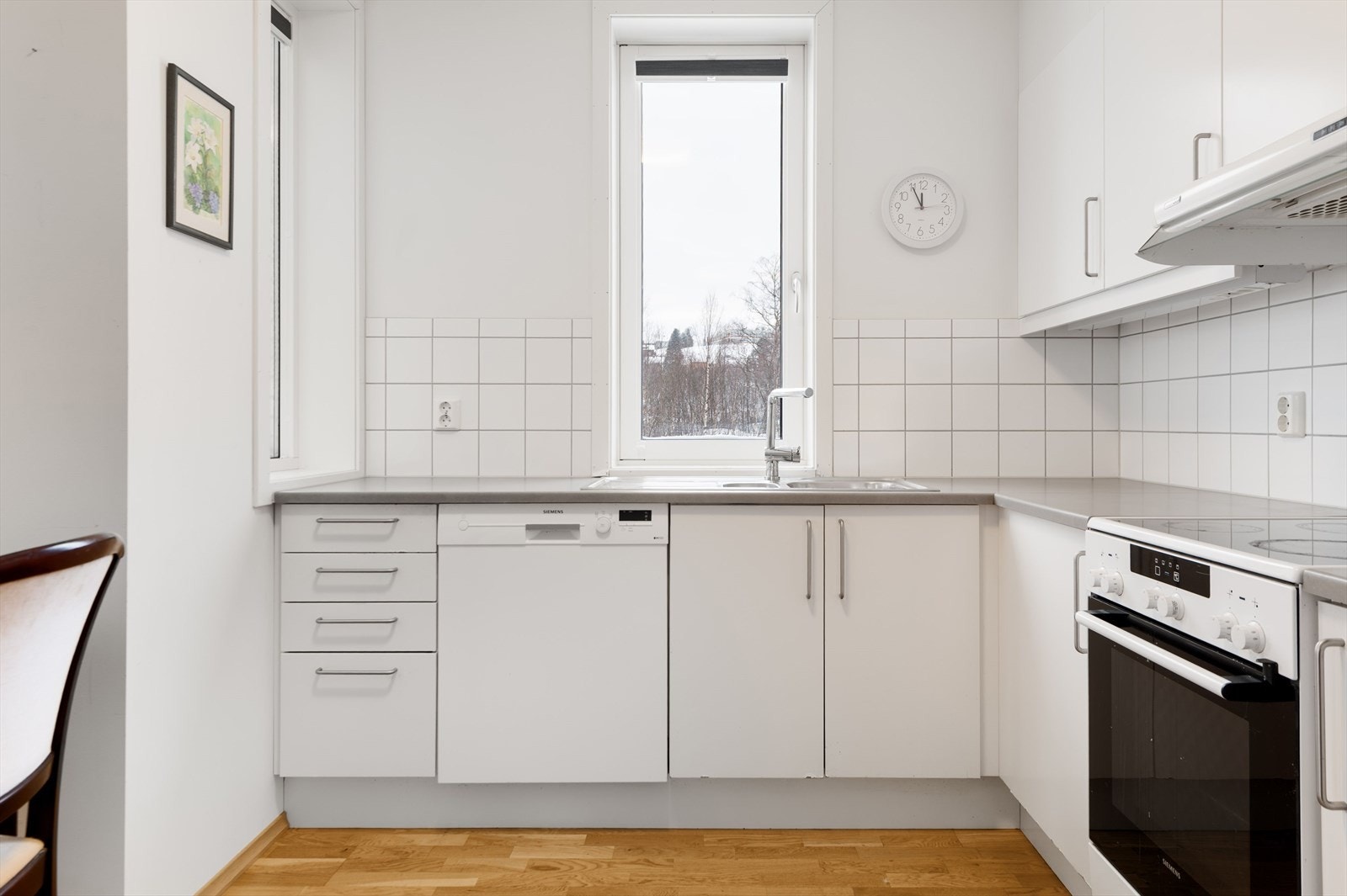 Lys kjøkkeninnredning med slette fronter, plass til frittstående hvitevarer. Galleribilde