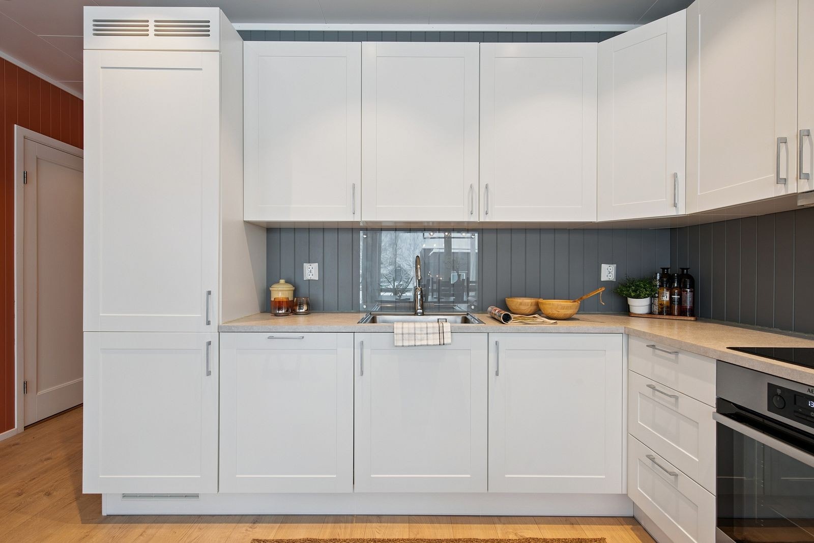 Pen kjøkkeninnredning fra Fossline med integrerte hvitevarer og downlights over benken. Galleribilde