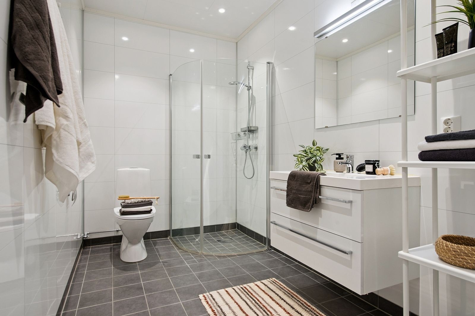 Badet er utstyrt med dusjhjørne og servant med skuffeseksjon. Galleribilde